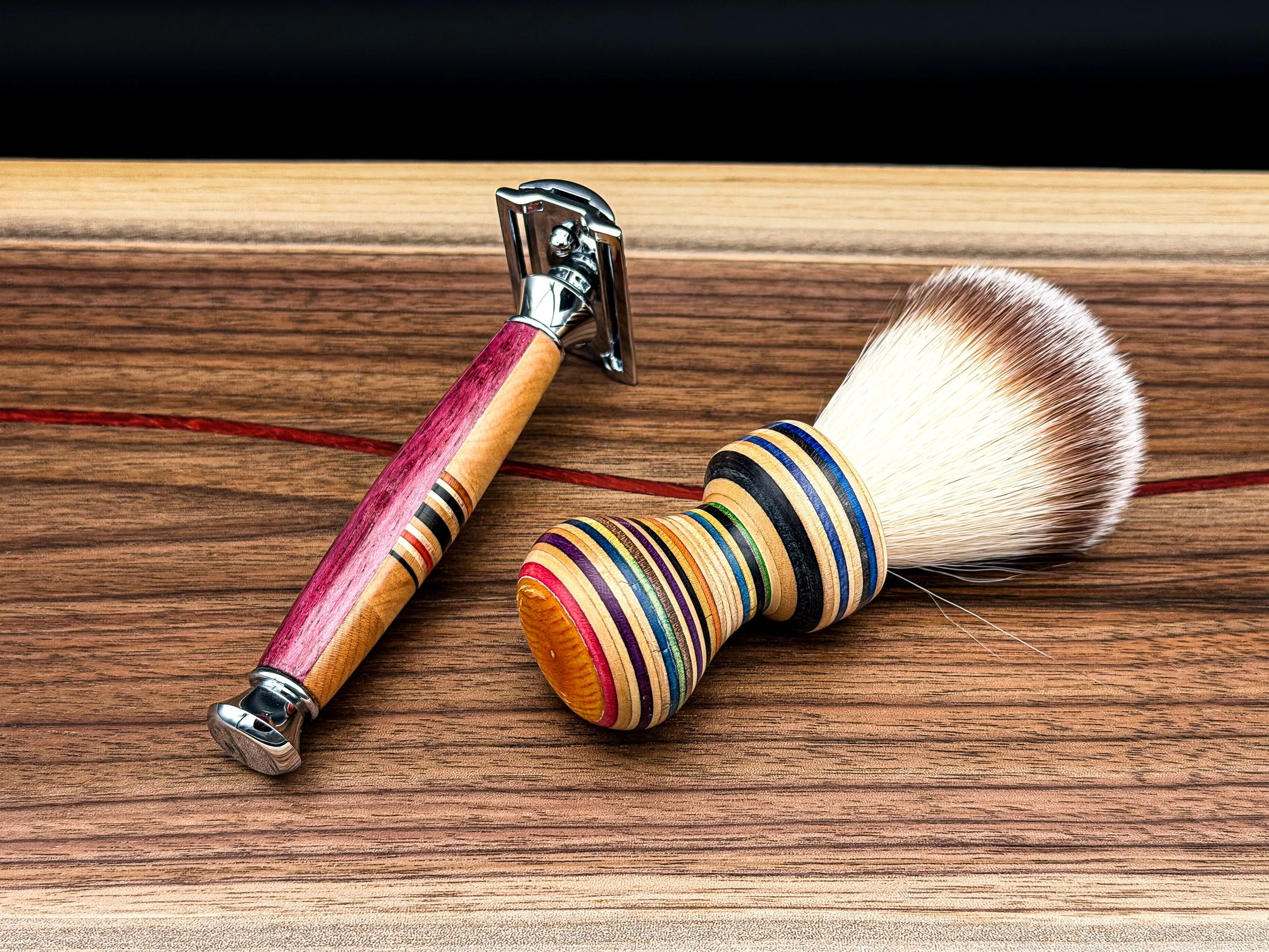 A handcrafted safety razor and shaving brush with recycled skateboard handles displayed on a walnut surface.