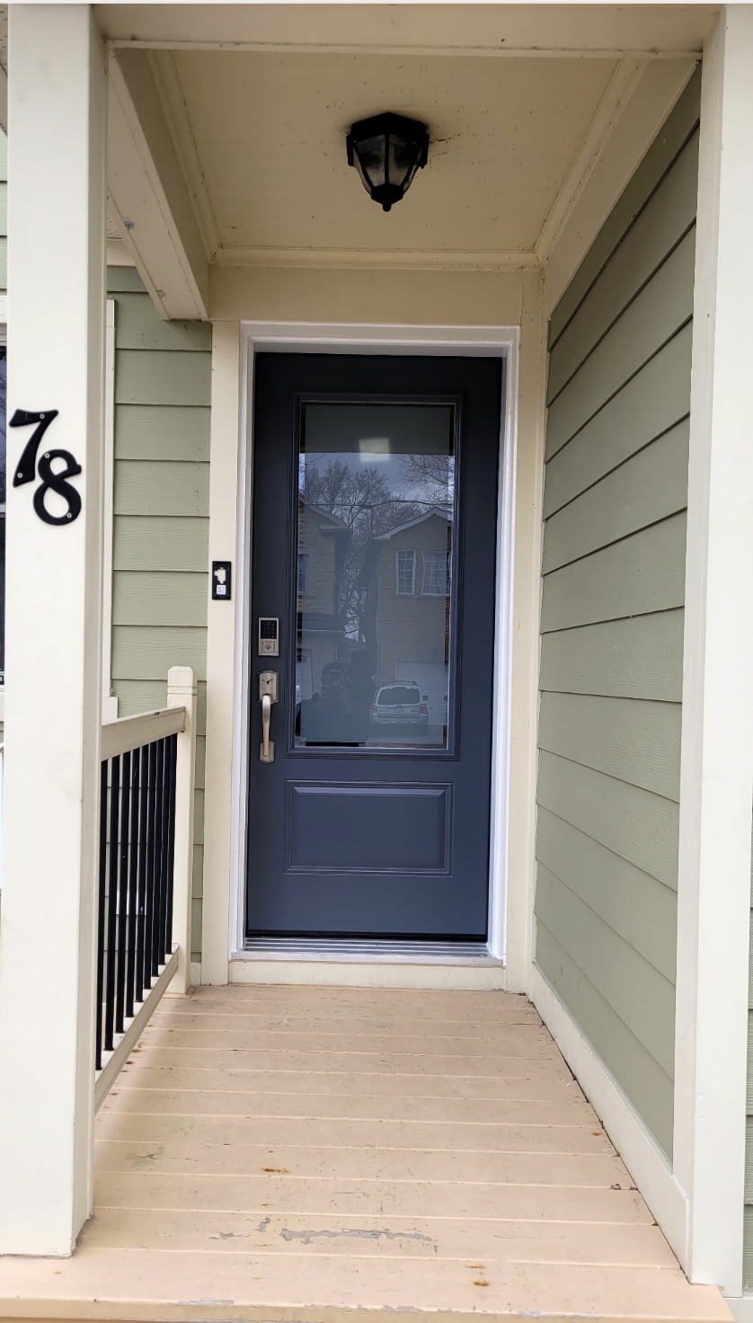Front porch with navy blue door, house number 78, black outdoor wall lantern, and light green siding.