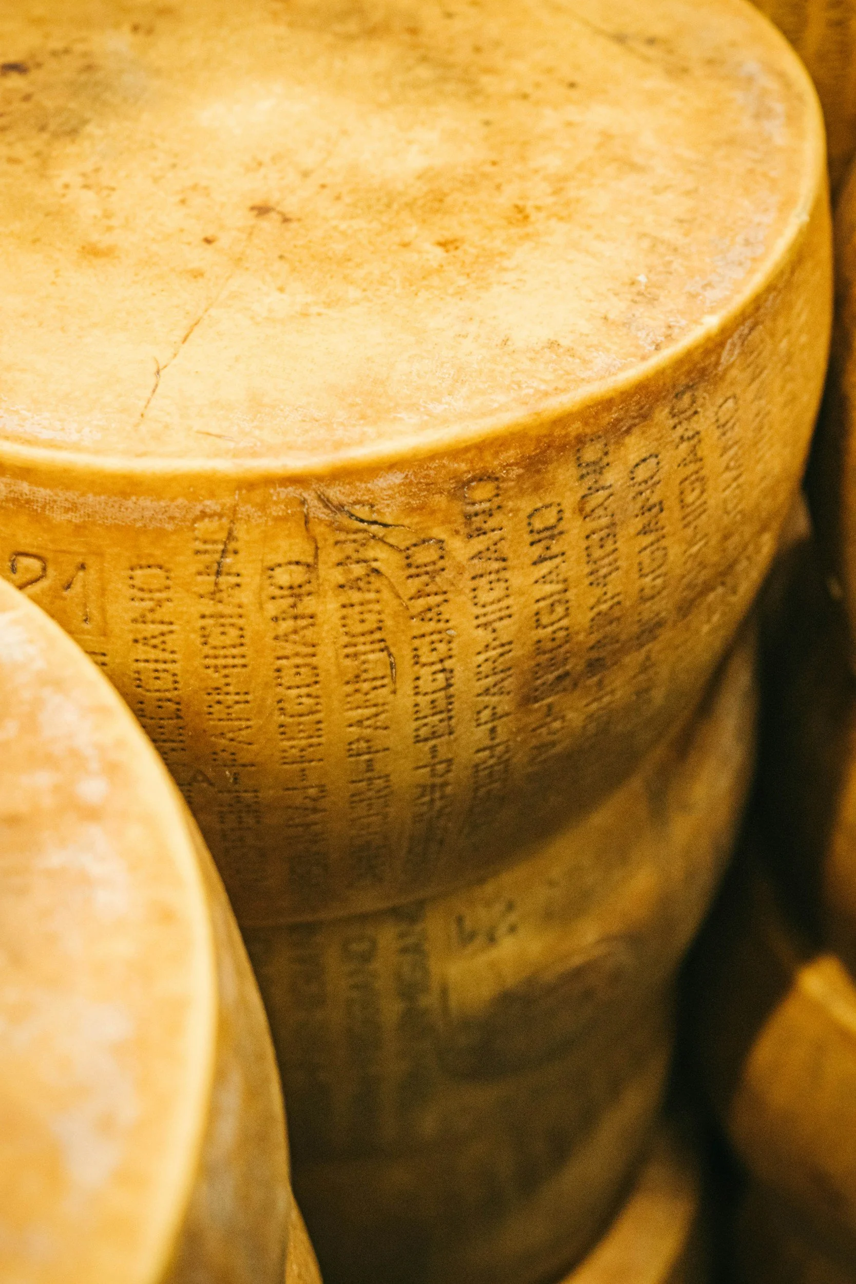 Close-up image of a golden wheel of Parmigiana Reggiano cheese with printed text on the rind.