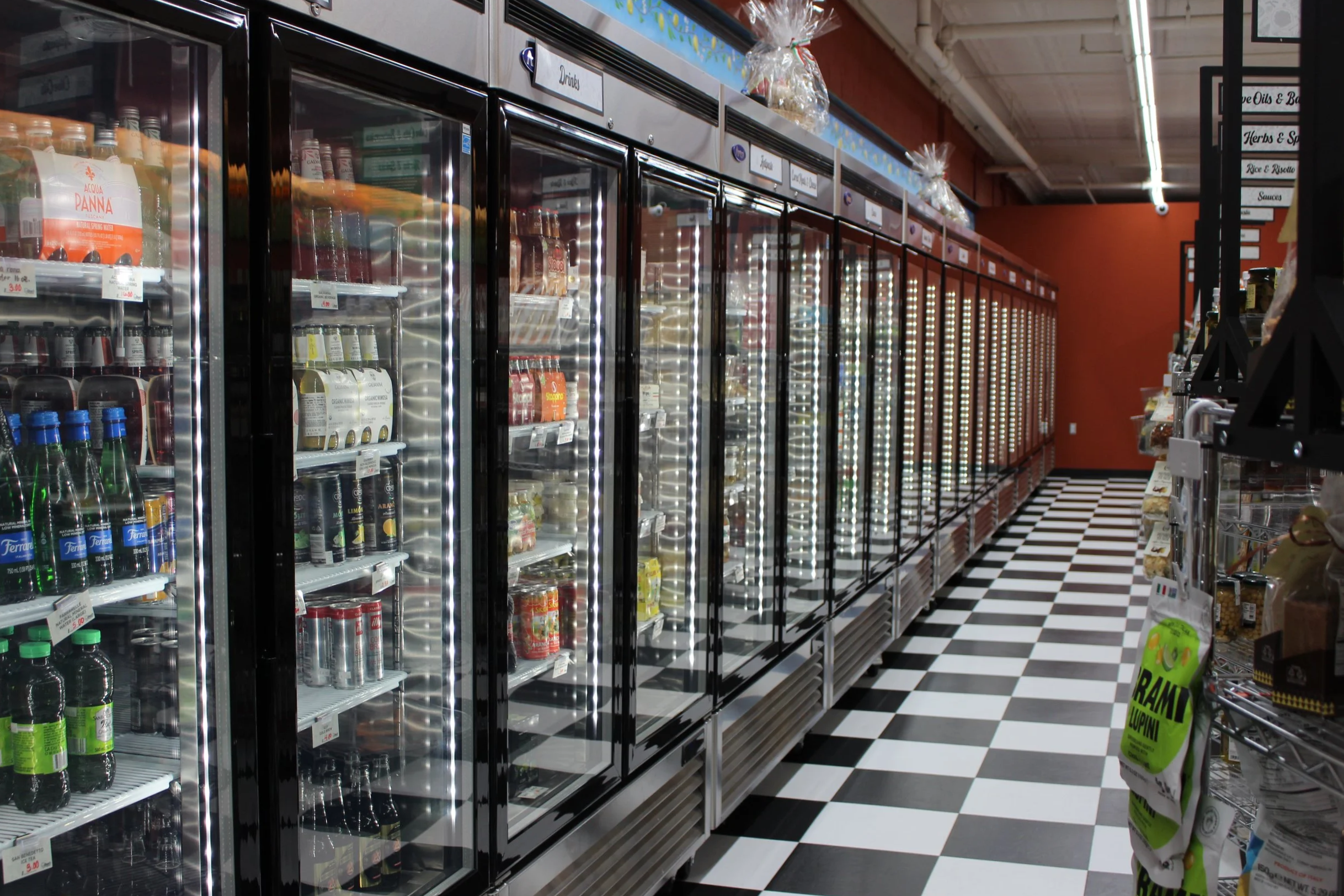 A long grocery aisle showing refrigerated and frozen Italian products. 