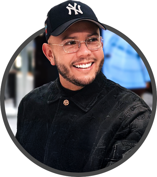 Lex Borrero wearing glasses, a navy New York Yankees baseball cap, and a black jacket, indoors with blurred background.