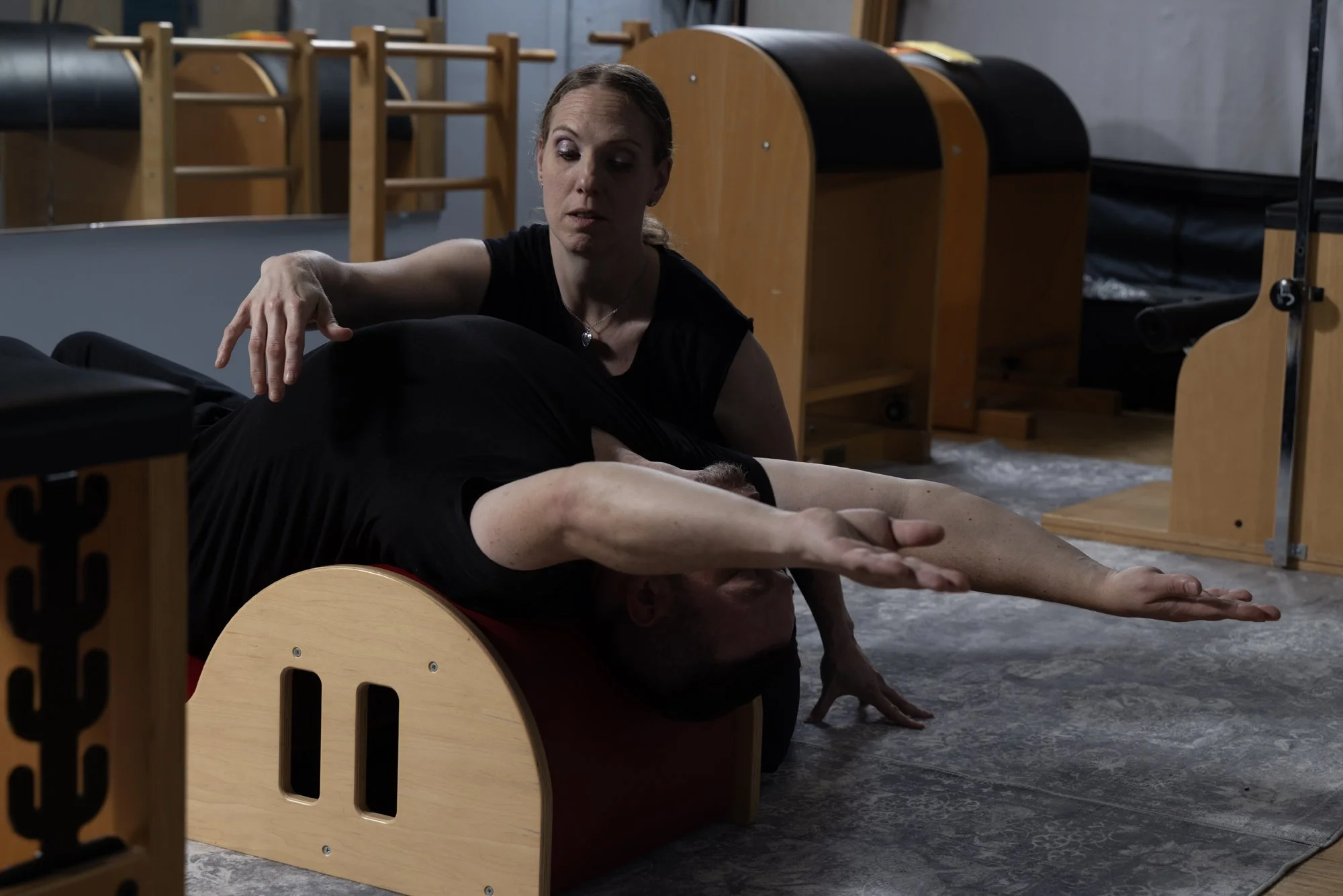 Pilates teacher helping client with lower back exercise.