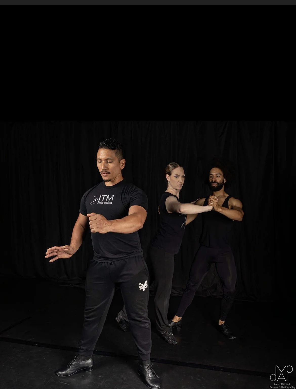 Couple learning to salsa dance together while teacher instructs them.