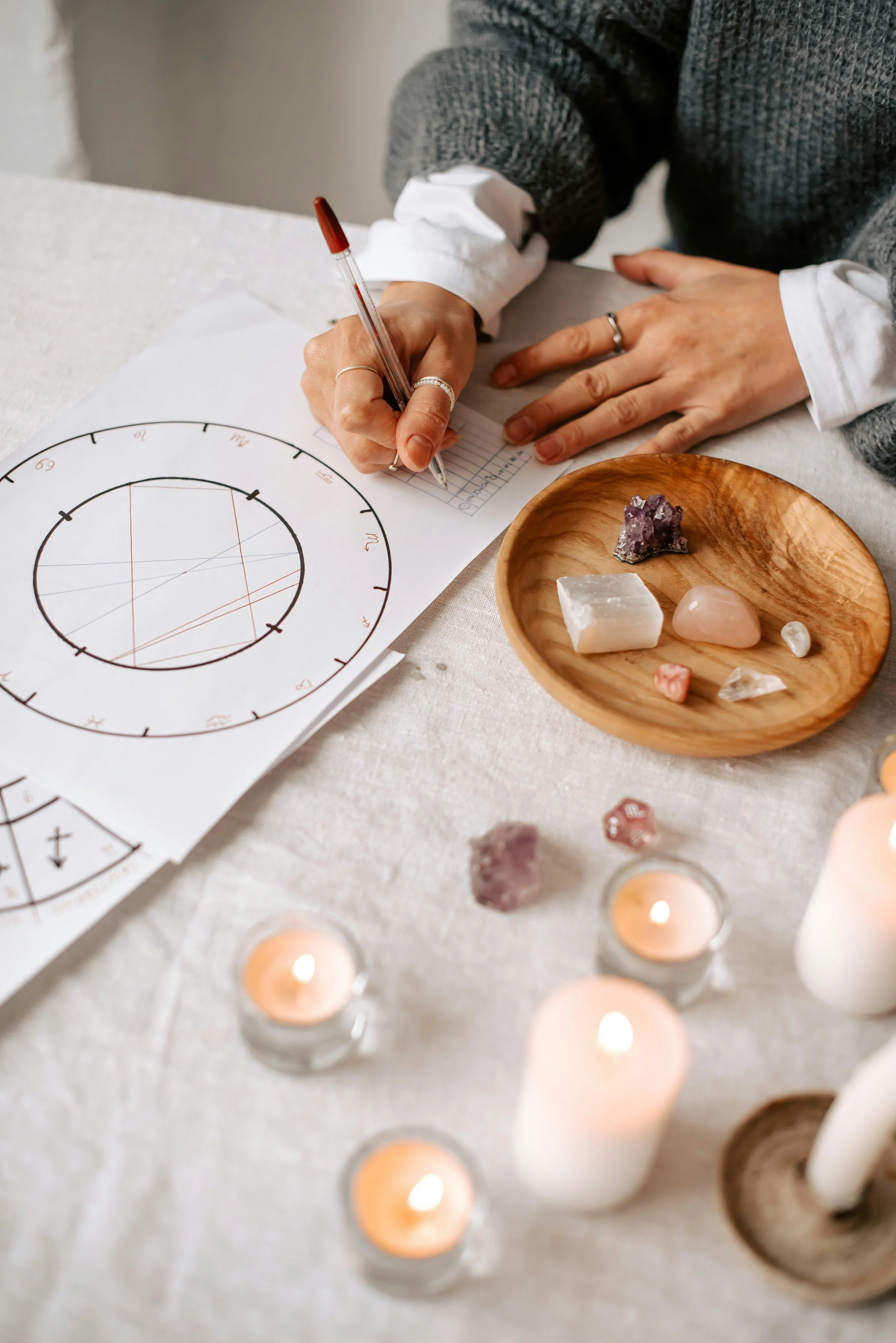 Hand-drawn natal chart on paper with incense, amethyst crystals, and a cup of tea