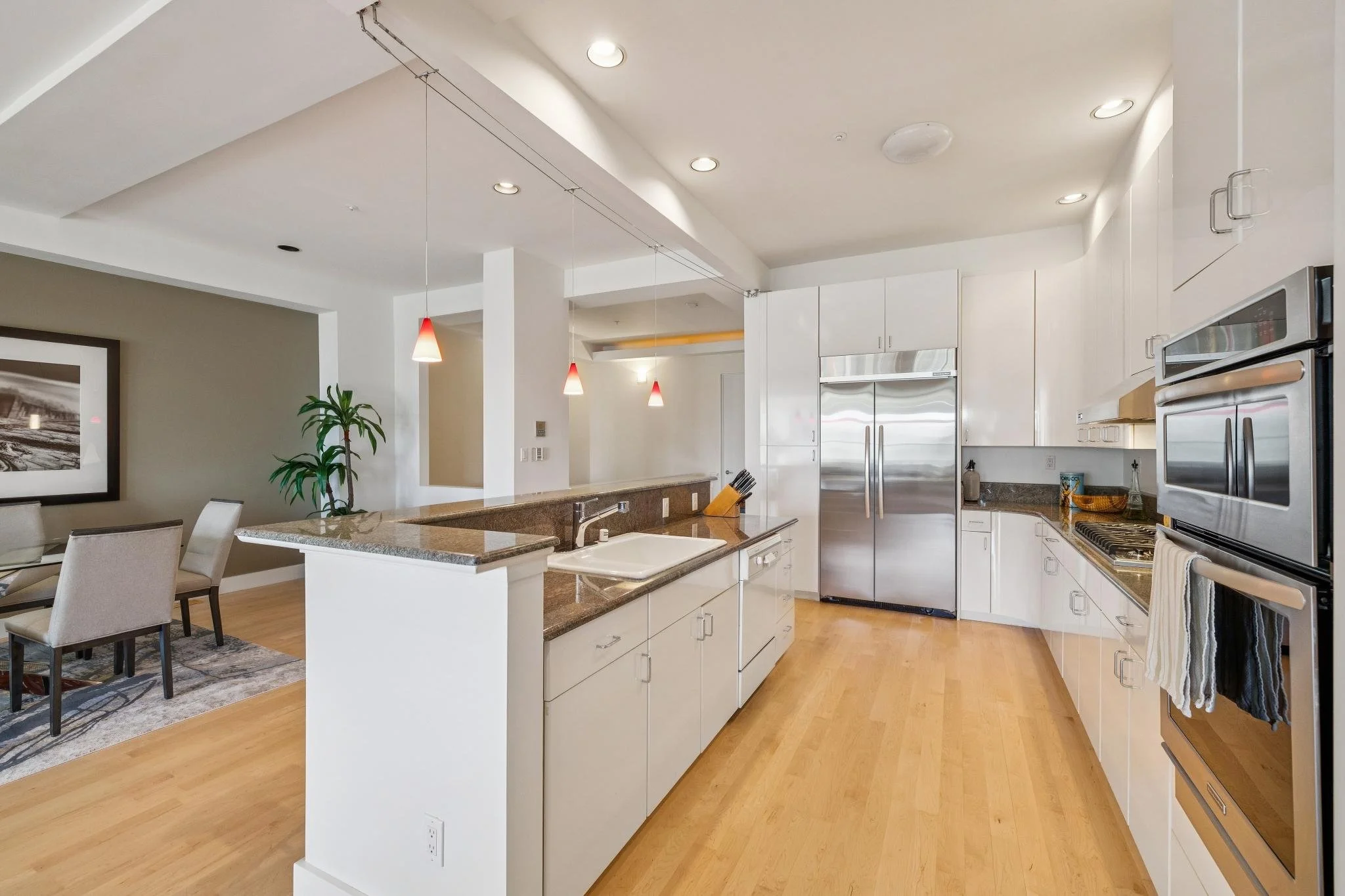 Modern kitchen with white cabinets, stainless steel appliances, granite countertops, and hardwood flooring.