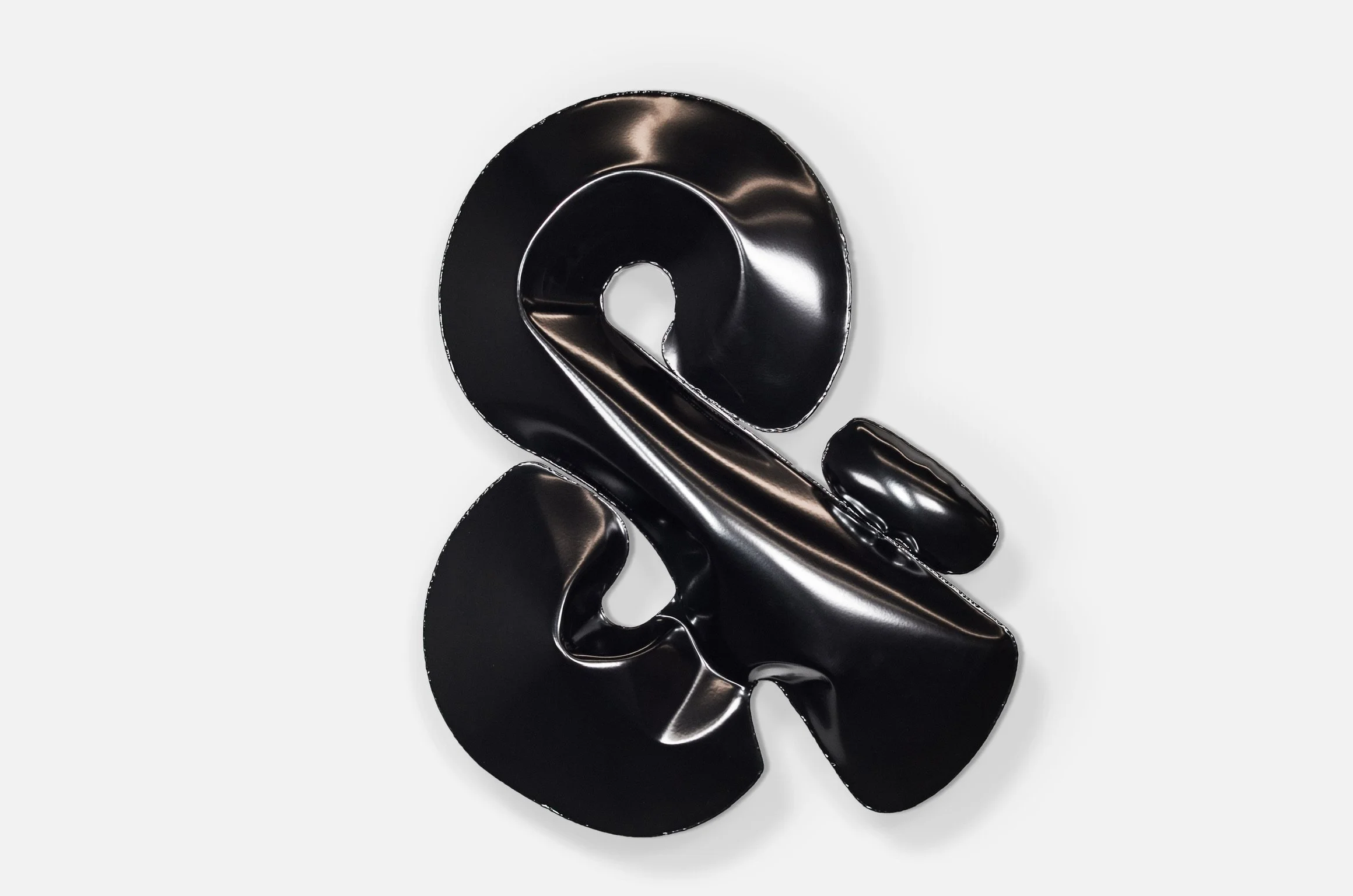 Black metallic sculpture with abstract shapes on a white background.