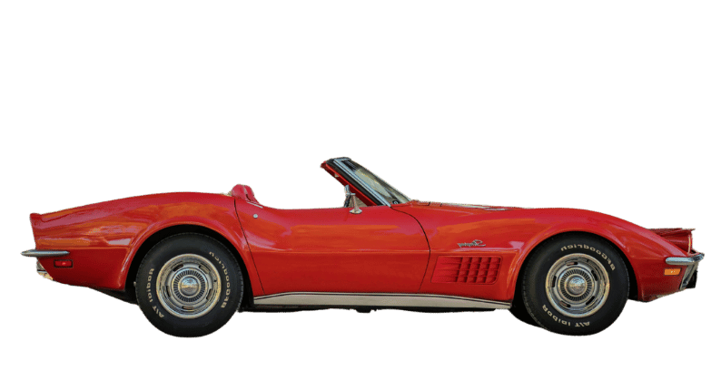 Red classic Chevrolet Corvette convertible car with black and white tires and chrome hubcaps, isolated on a white background.