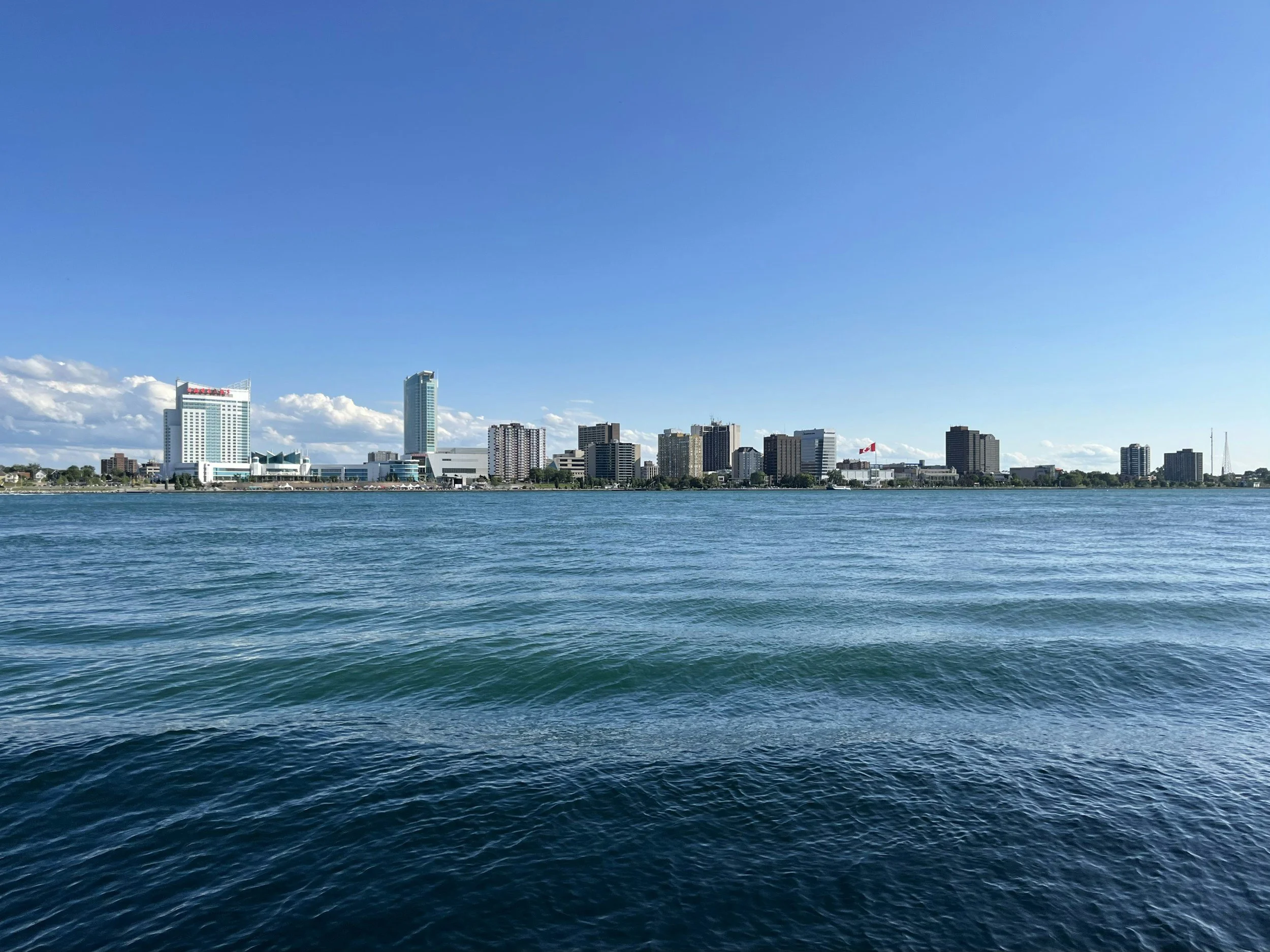 City skyline across a body of water on a clear day with blue sky and a few clouds.