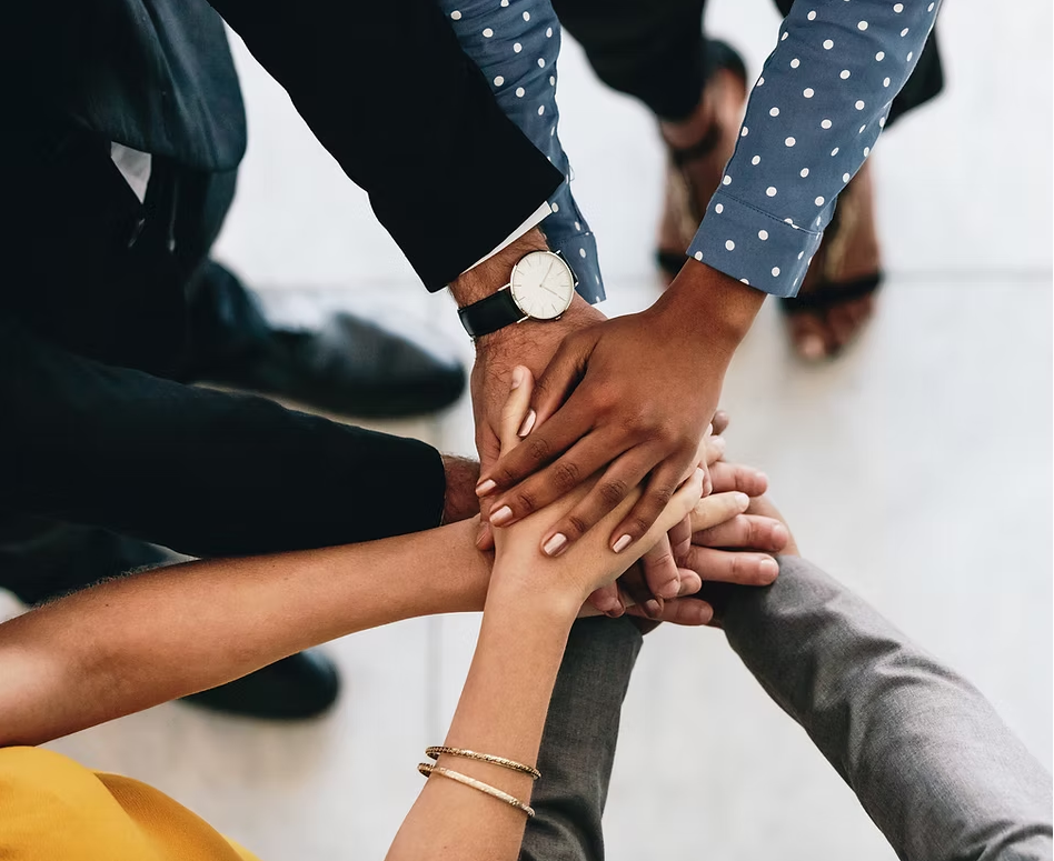 Multiple people stacking their hands together in a group gesture.