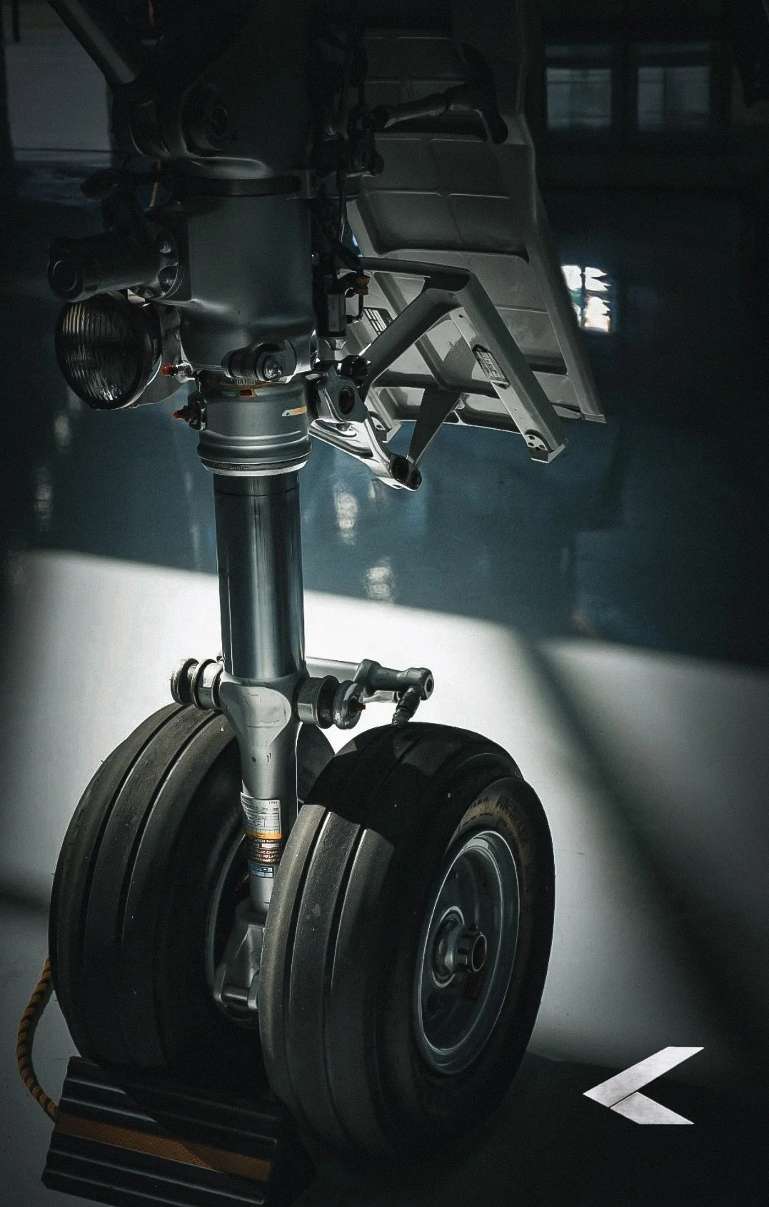Close-up of a motorcycle front wheel, suspension, and headlight in a workshop setting.