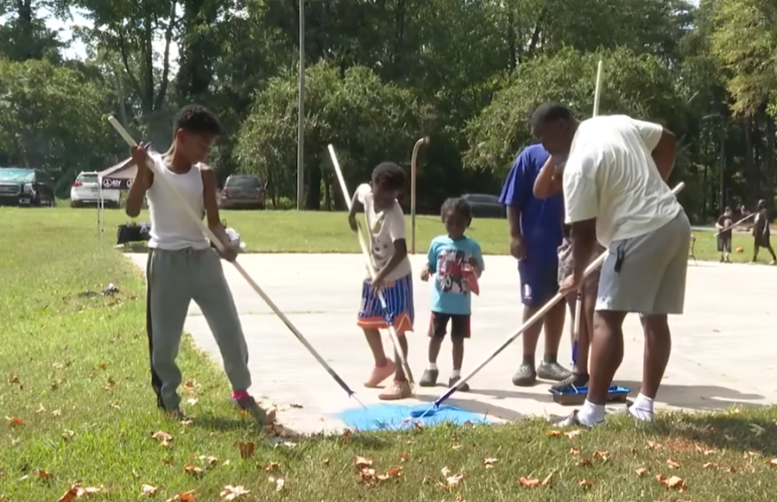 A group of Charlotte youth painting a basket ball court blue.
