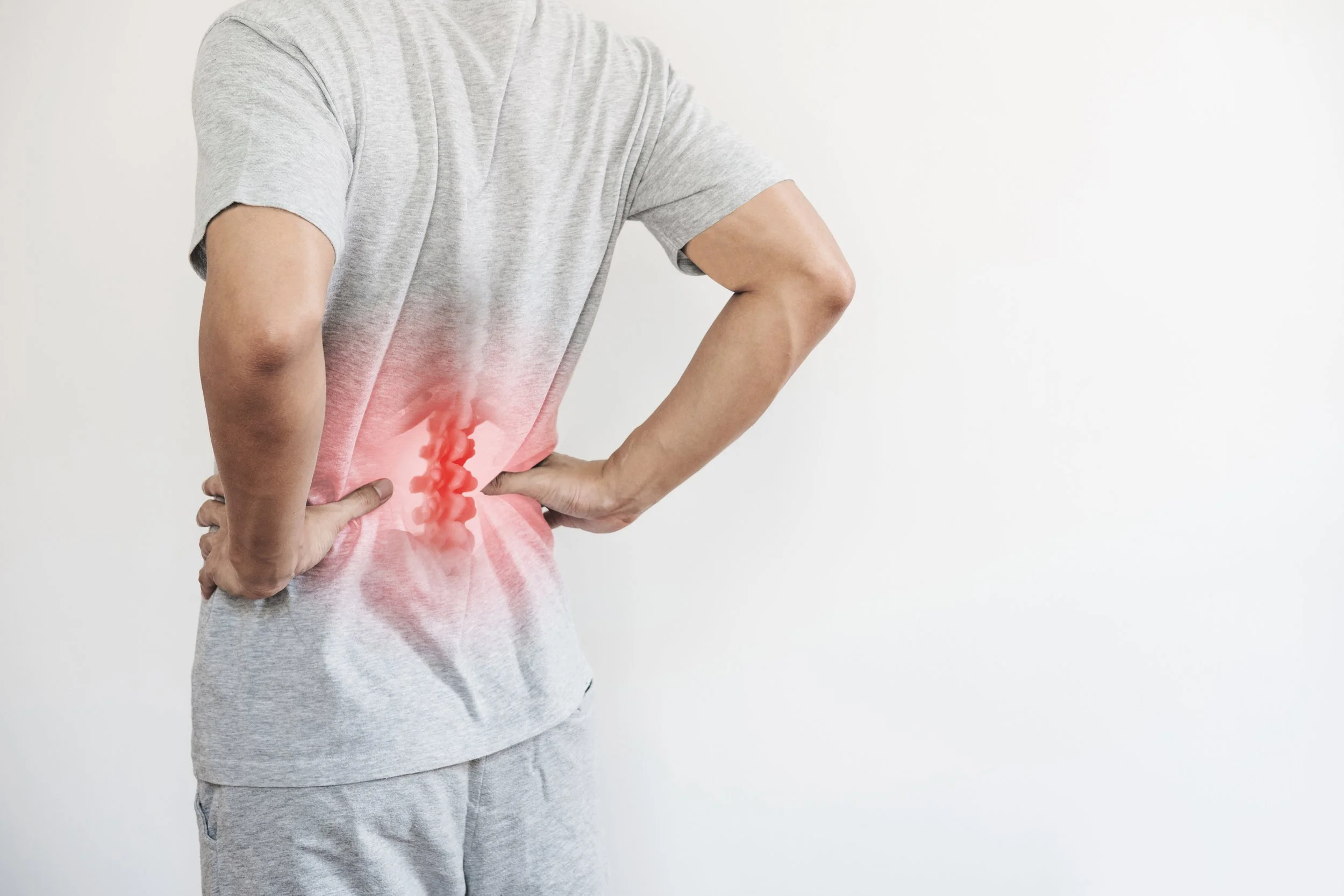 Man touching his lower back showing lumbago pain point, receiving physical therapy consultation at Signature PT in Manhattan.