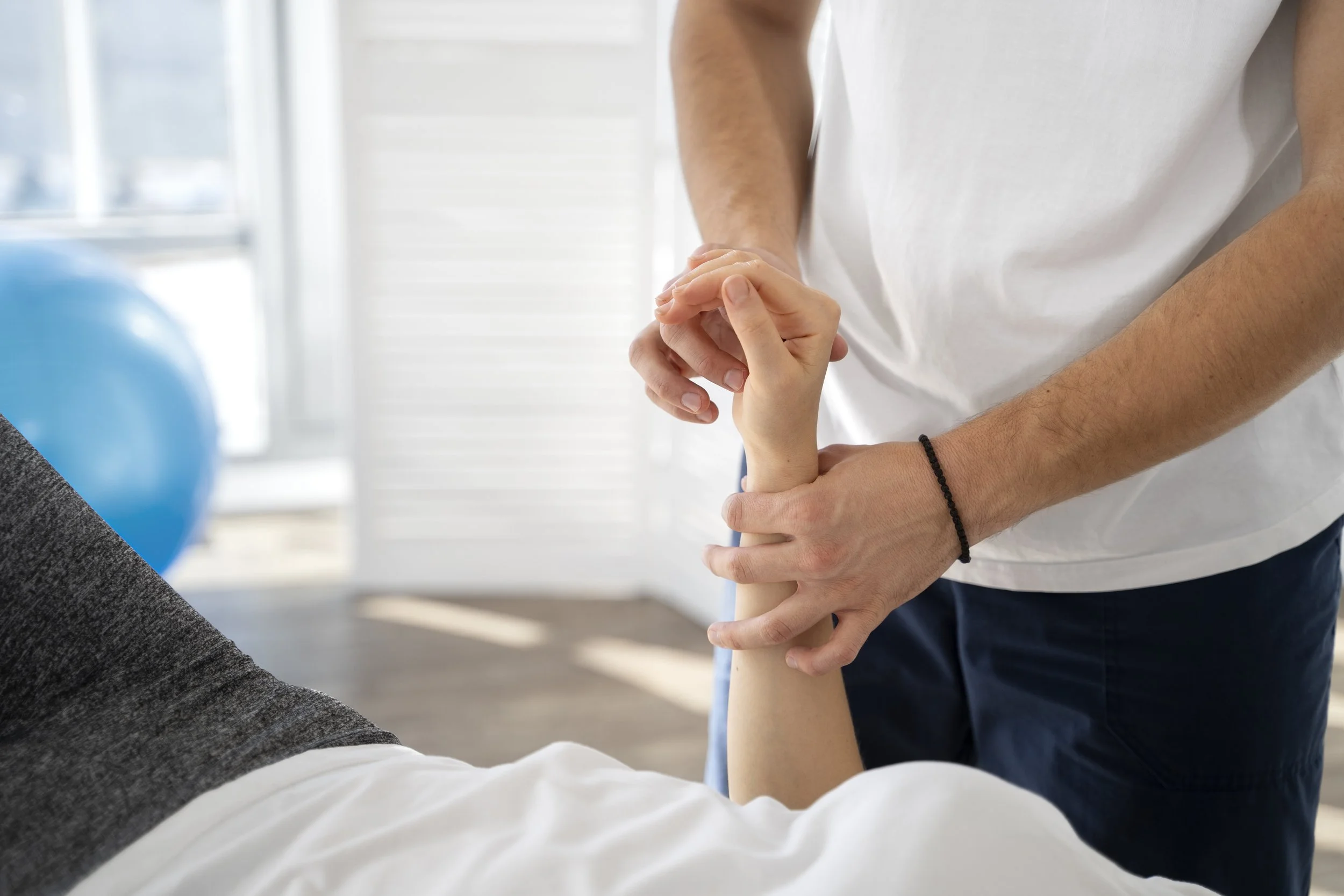 A professional physical therapist perform manual wrist joint mobilization and structural re-alignment therapy on a patient to restore function and relieve pain.