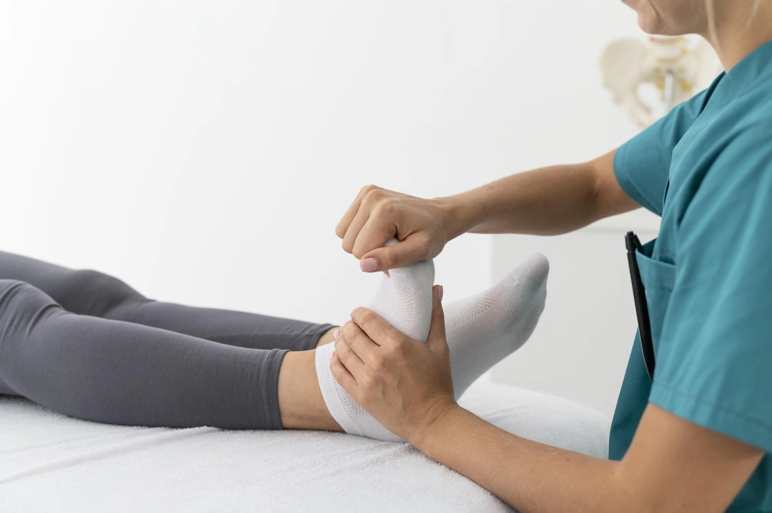 A professional physical therapist at Signature PT perform manual joint mobilization and passive stretching on a patient’s foot on a treatment table.