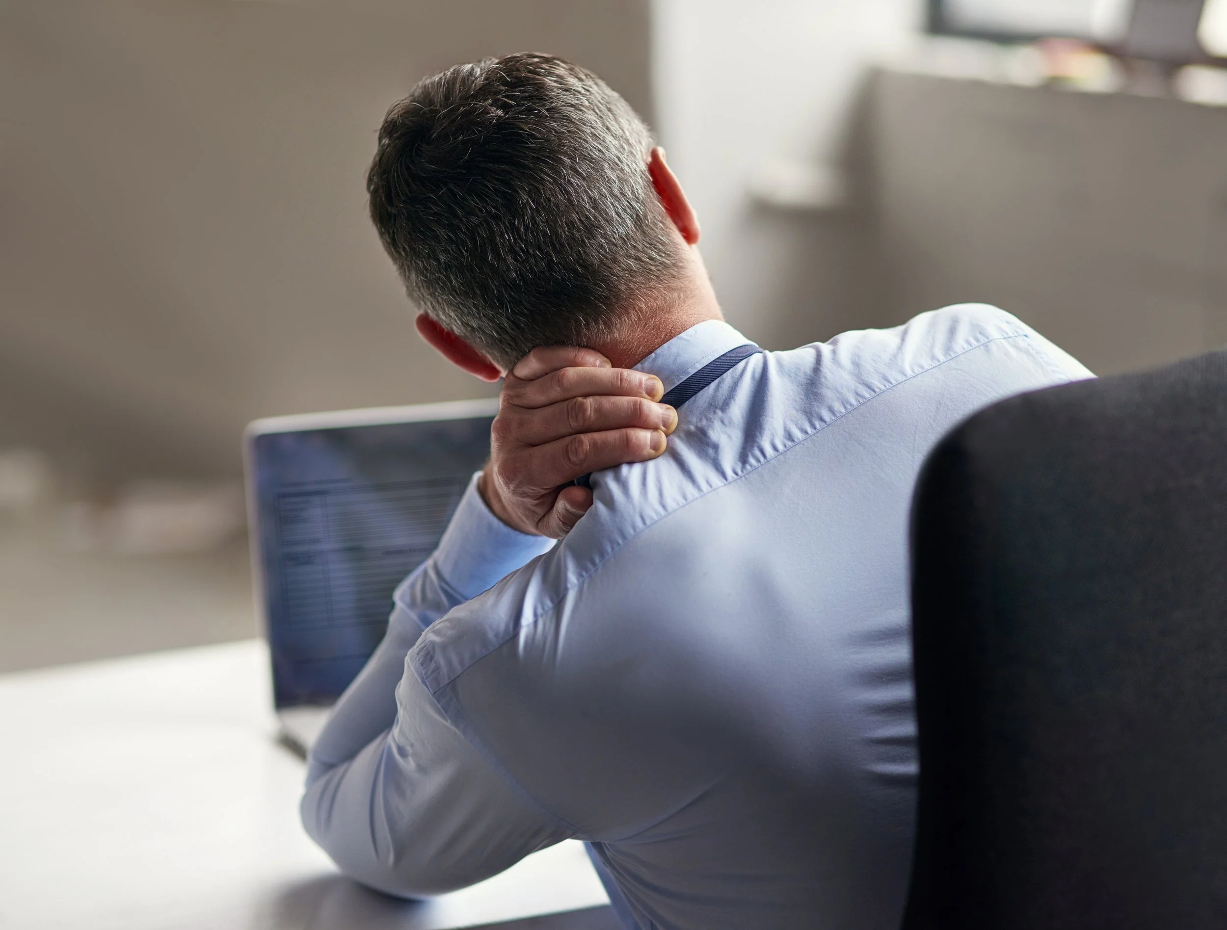 A person experiencing sharp neck pain and cervical tension, seeking expert physical therapy and spinal alignment at Signature PT in Manhattan.