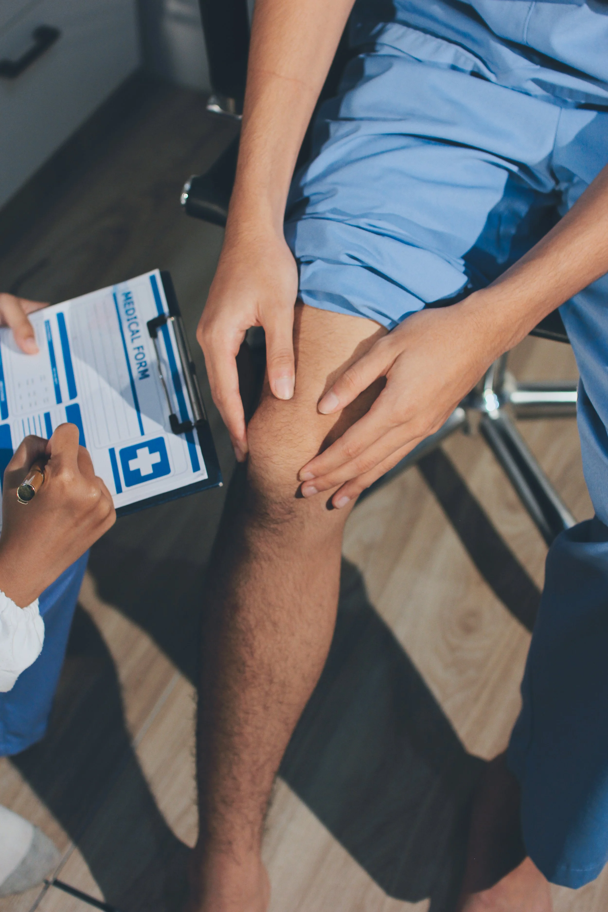 A physical therapist at Signature PT performing a clinical evaluation on an injured worker while completing the required medical forms for a Worker's Comp claim.