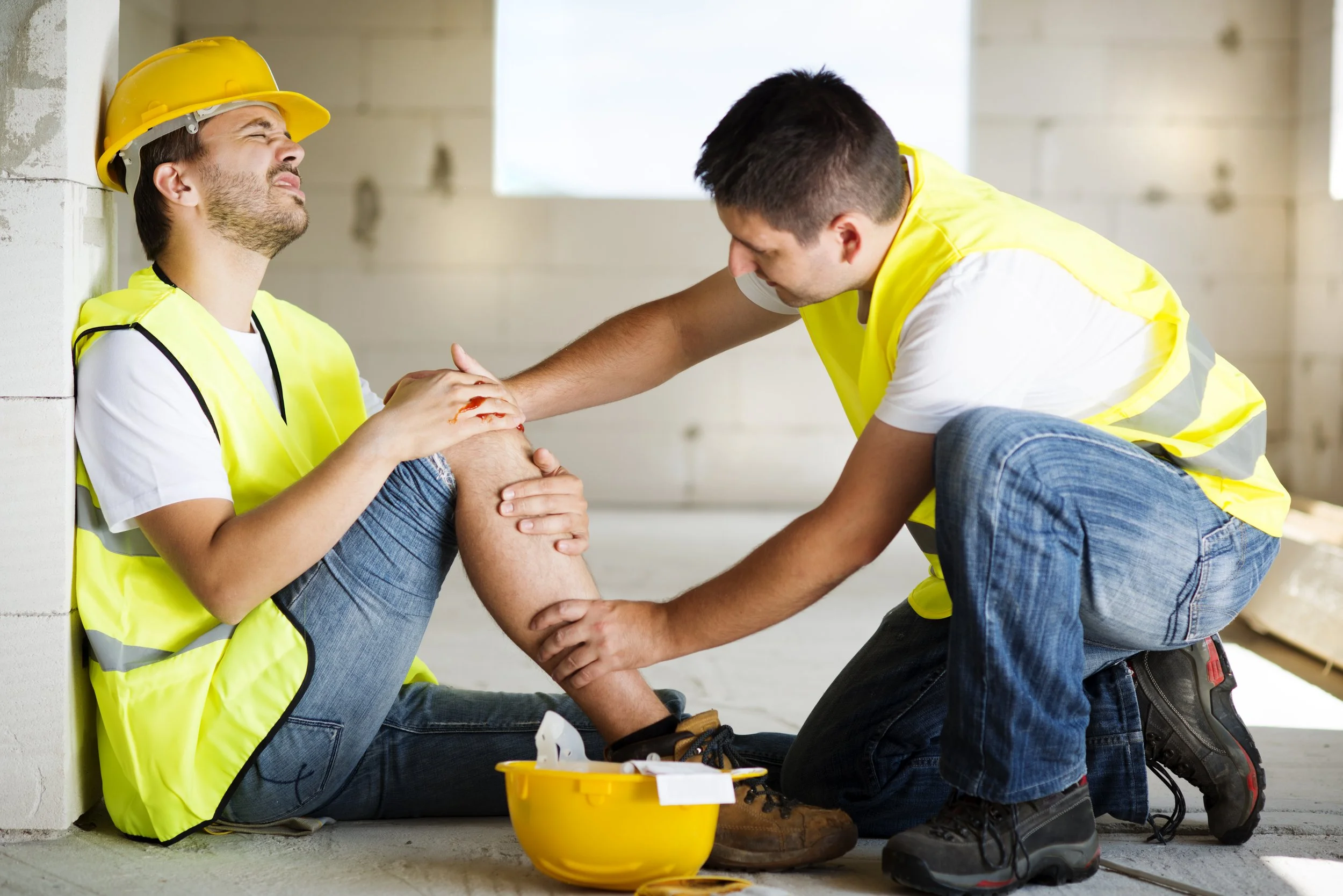 An injured construction worker being assisted by a colleague at a Manhattan building site, seeking a Worker’s Compensation evaluation at Signature PT.
