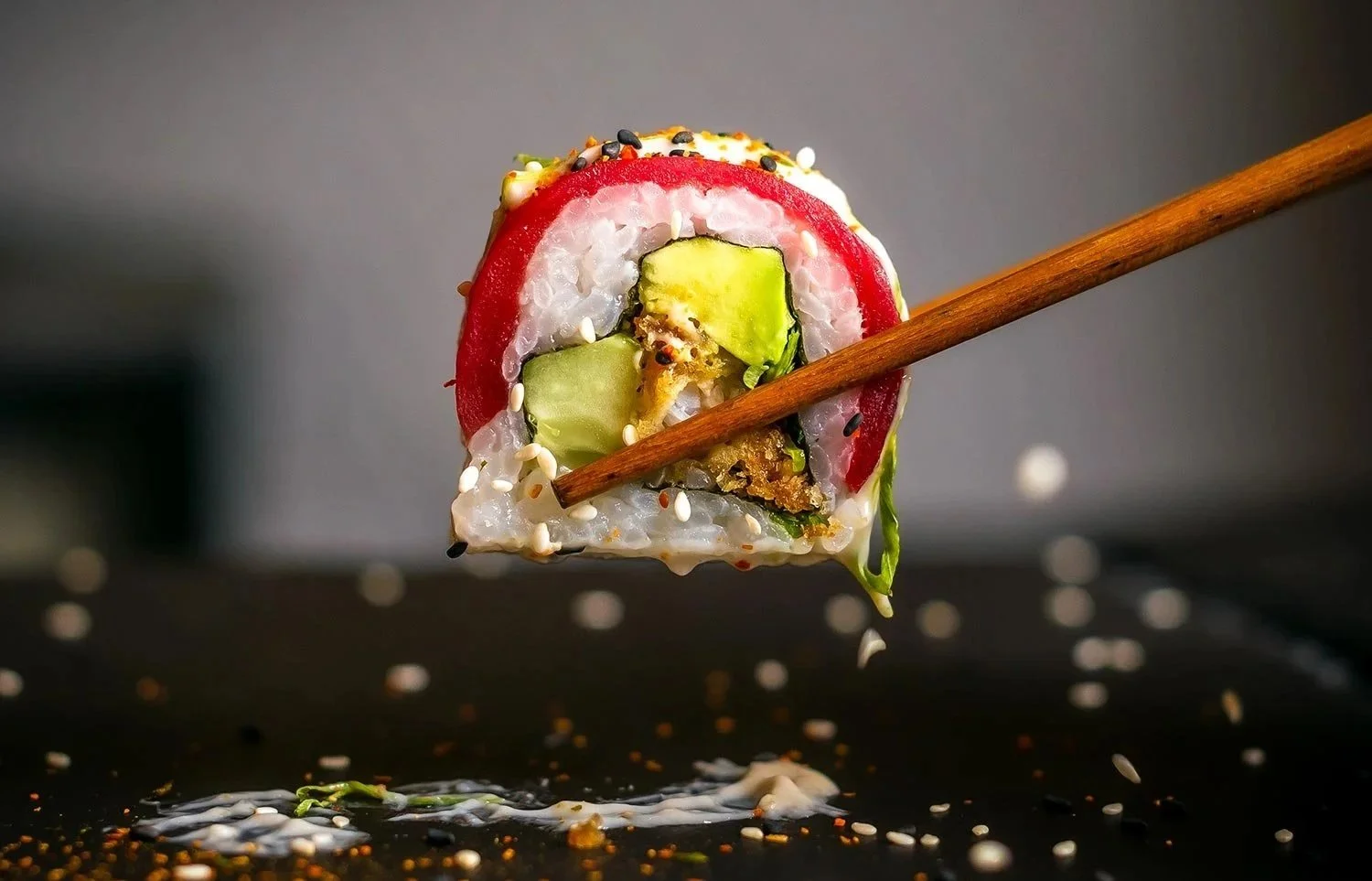 Sushi con pepino, aguacate y semillas, con palillo de madera, sobre una superficie negra