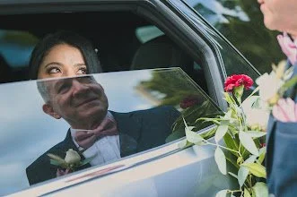 Joven mujer en coche mirándose a un hombre con flores, en un encuentro emotivo.