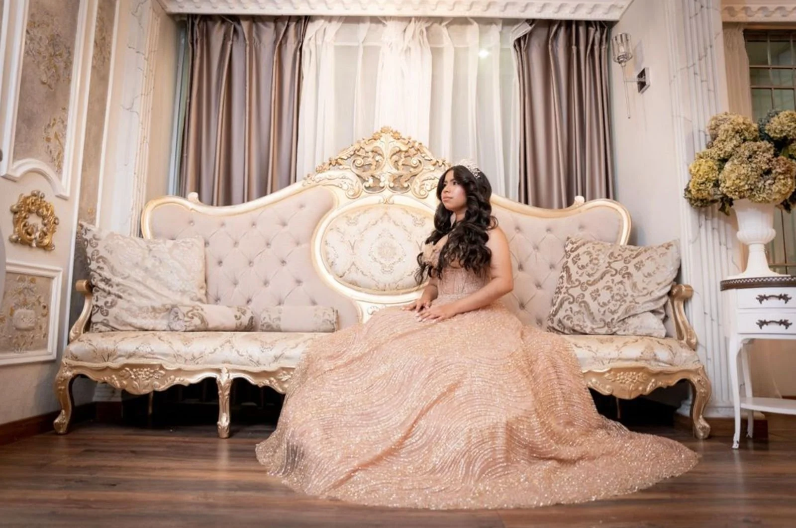 Joven con vestido de gala en un sofá con decoraciones elegantes en un ambiente de estilo clásico.