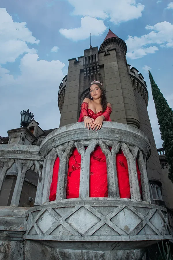 Una joven con un vestido rojo y una tiara en el castillo de un cuento de hadas.