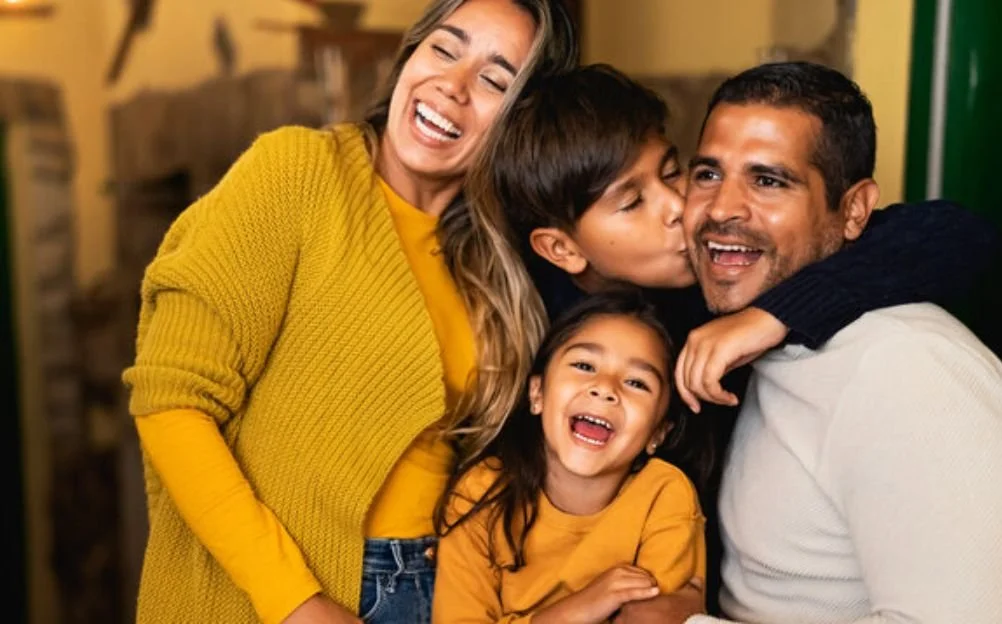 Familia feliz abrazándose y riendo en interior.