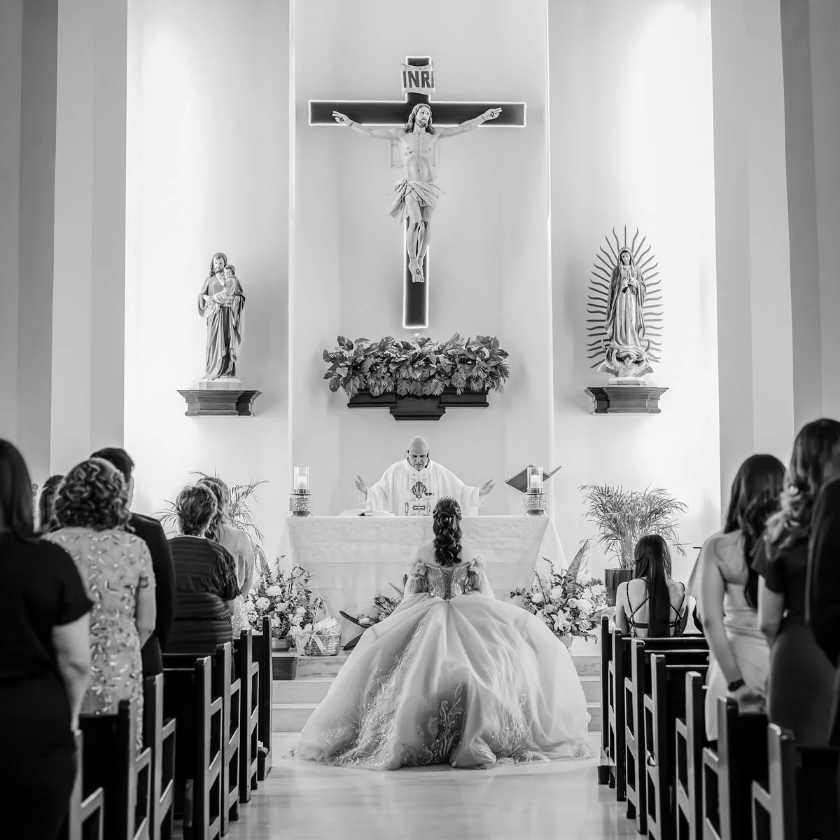 Una pareja en una ceremonia de boda religiosa en una iglesia, con un sacerdote en el altar y la novia con vestido de novia en el centro, rodeada de invitados.