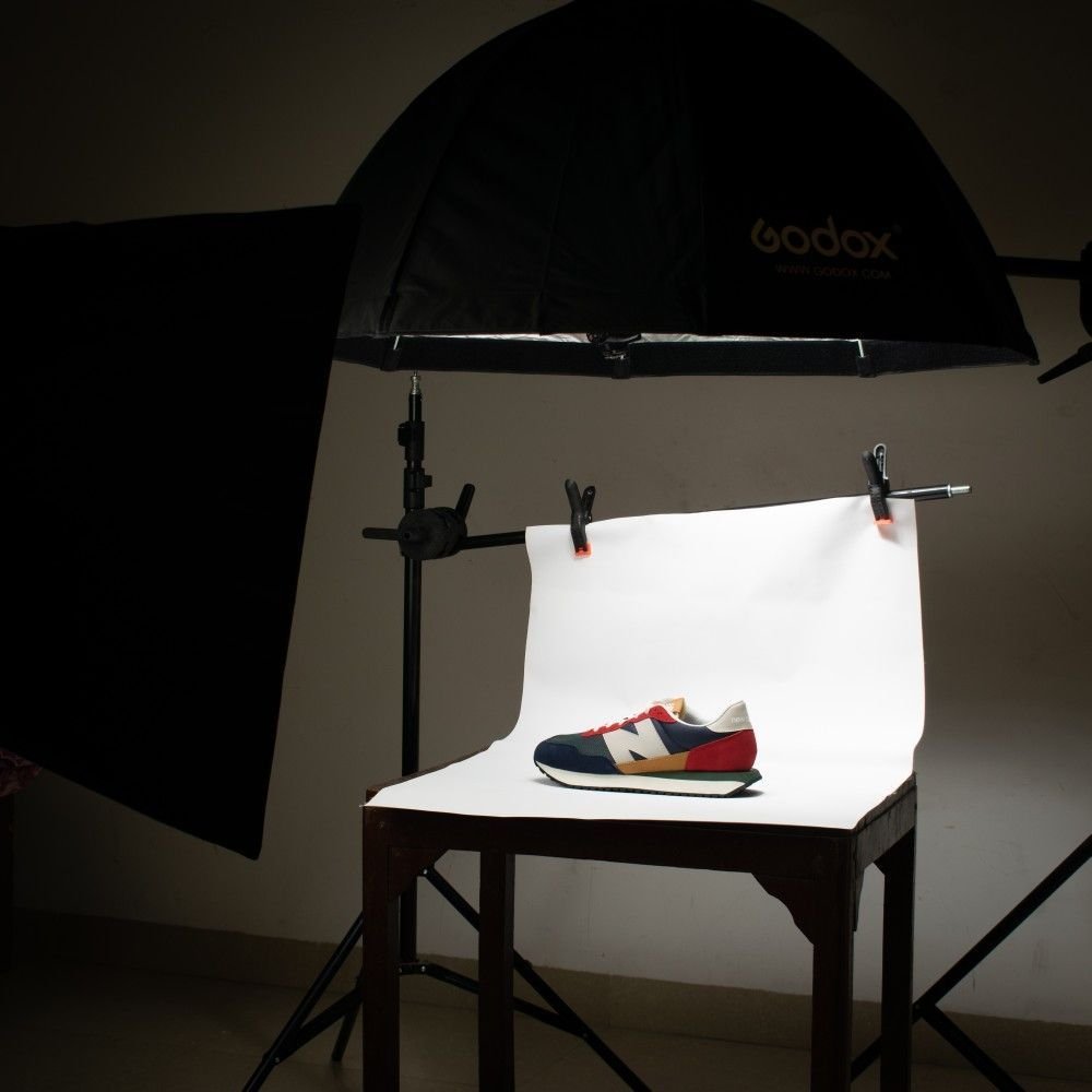 Zapato deportivo en un estudio de fotografía con fondo blanco, iluminación profesional y equipo de fotografía.