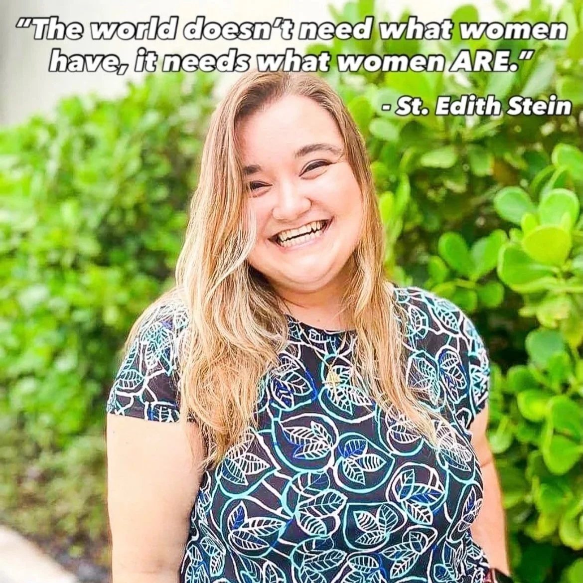 A smiling woman with long, wavy blonde hair, wearing a black top with a blue and white leaf pattern, standing outdoors with green foliage in the background. There is a quote at the top that reads, 'The world doesn't need what women have, it needs what women ARE.' attributed to St. Edith Stein.