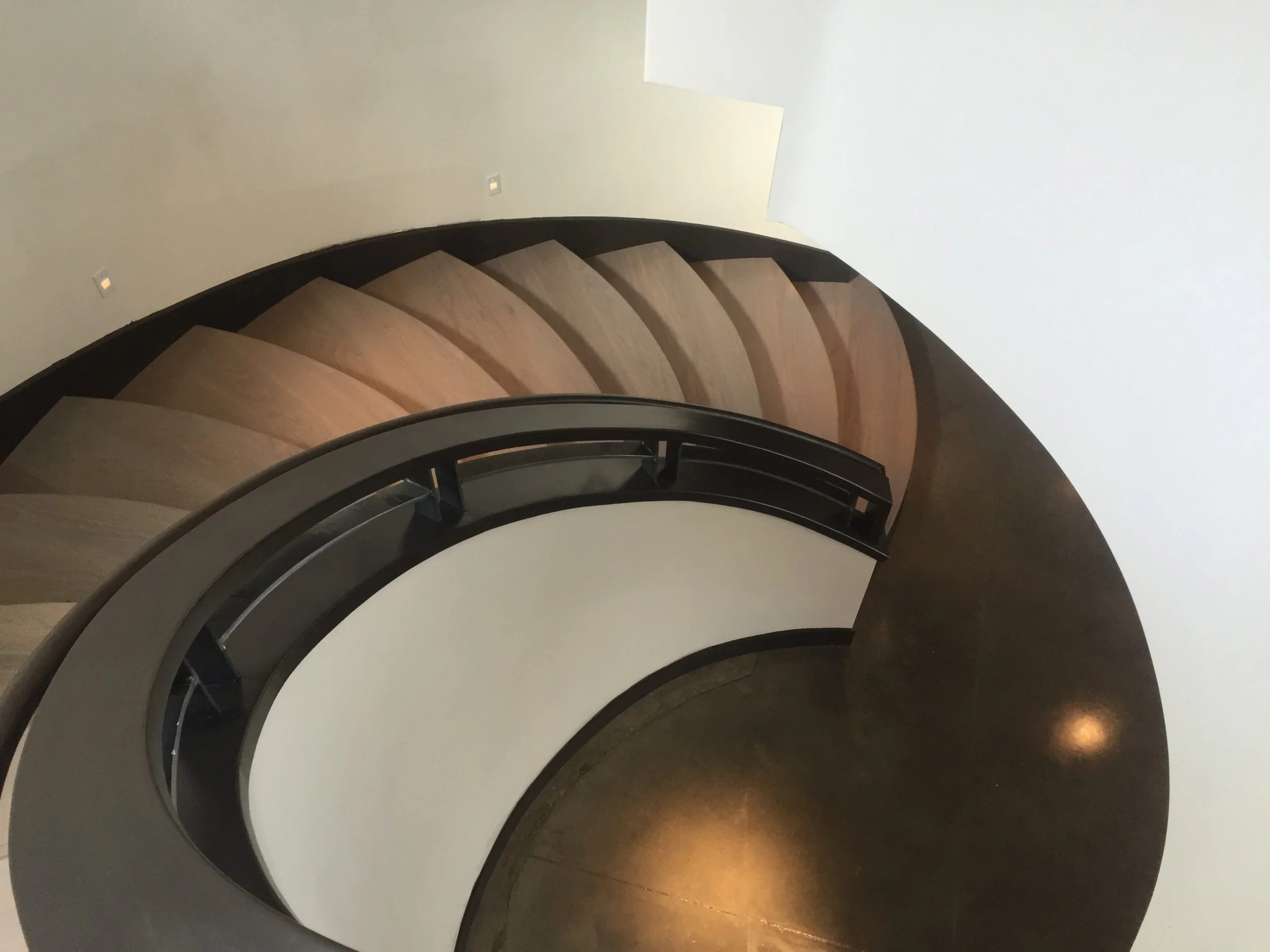 Custom steel stair grabrail flowing down curved stair