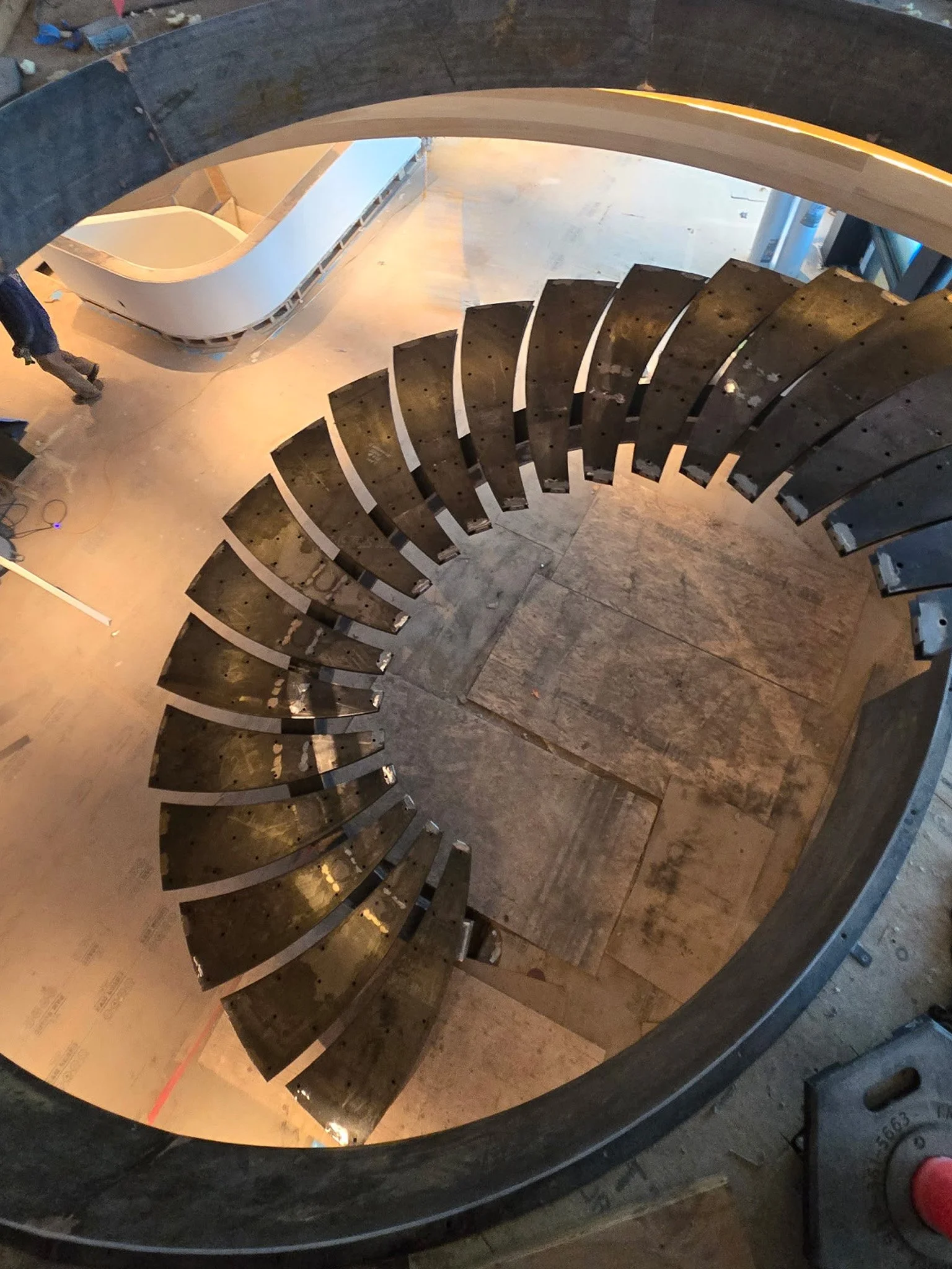A spiral staircase under construction viewed from above, showing the steps and the inner railing.