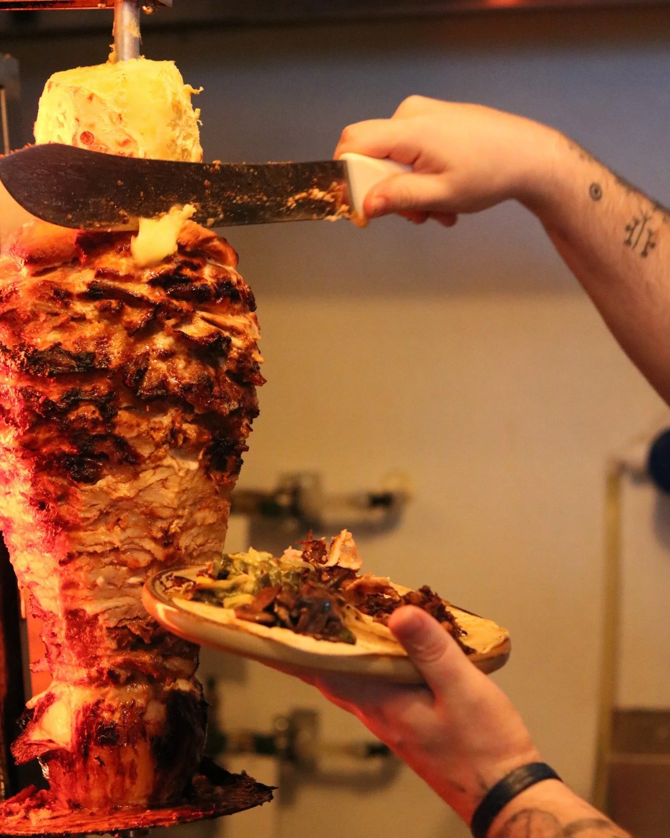 The blade comes off the trompo and the pi&ntilde;a drops straight onto the plate.
This is the move that can't be faked &mdash; pork stacked and spinning, charred at the edges, carved to order in one motion.
No pre-cut trays. No microwave. Just fire, 