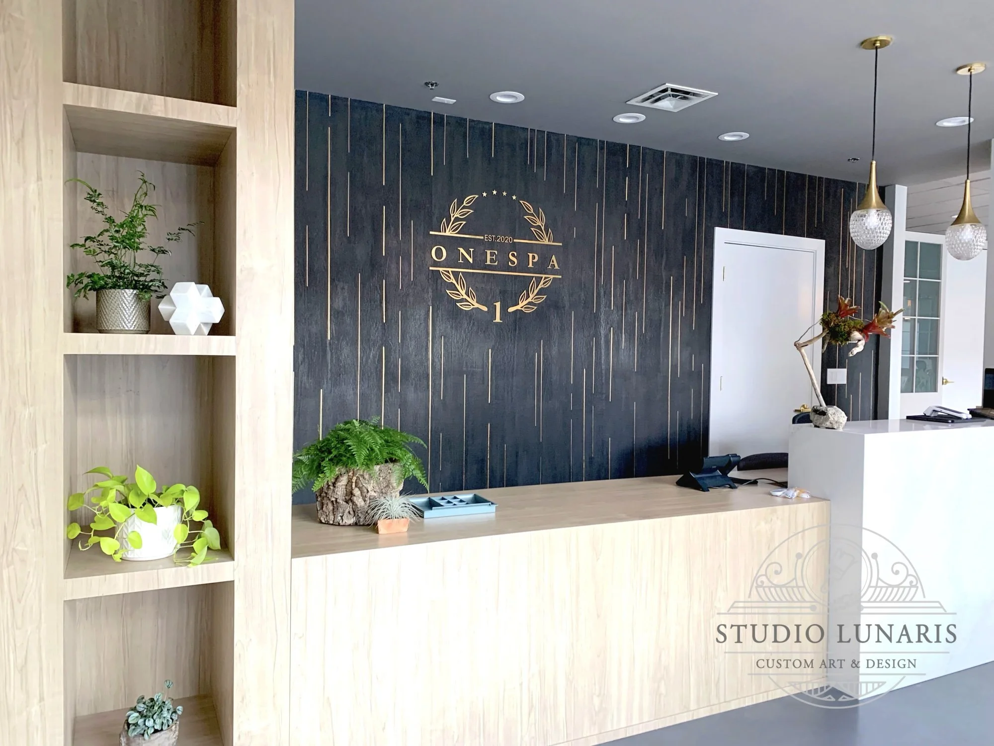 Medical spa lobby area accent wall with a marmorino charcoal background and faux inlay gold accents