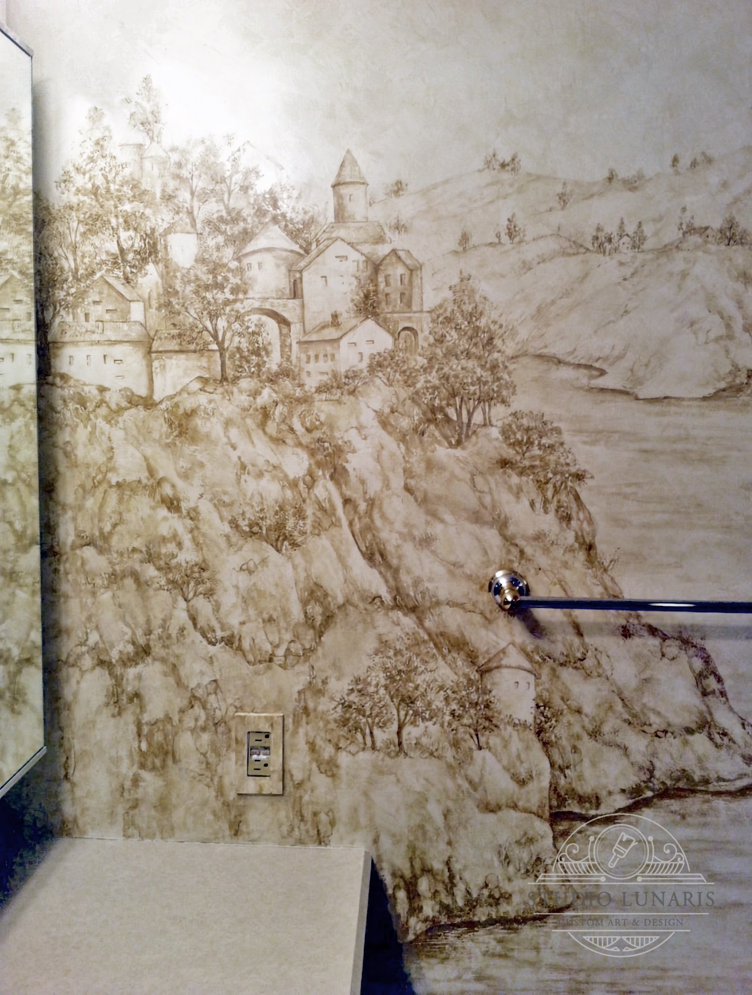 Bathroom mural with a fantasy, Italian coastal mountain scene in sepia tones.