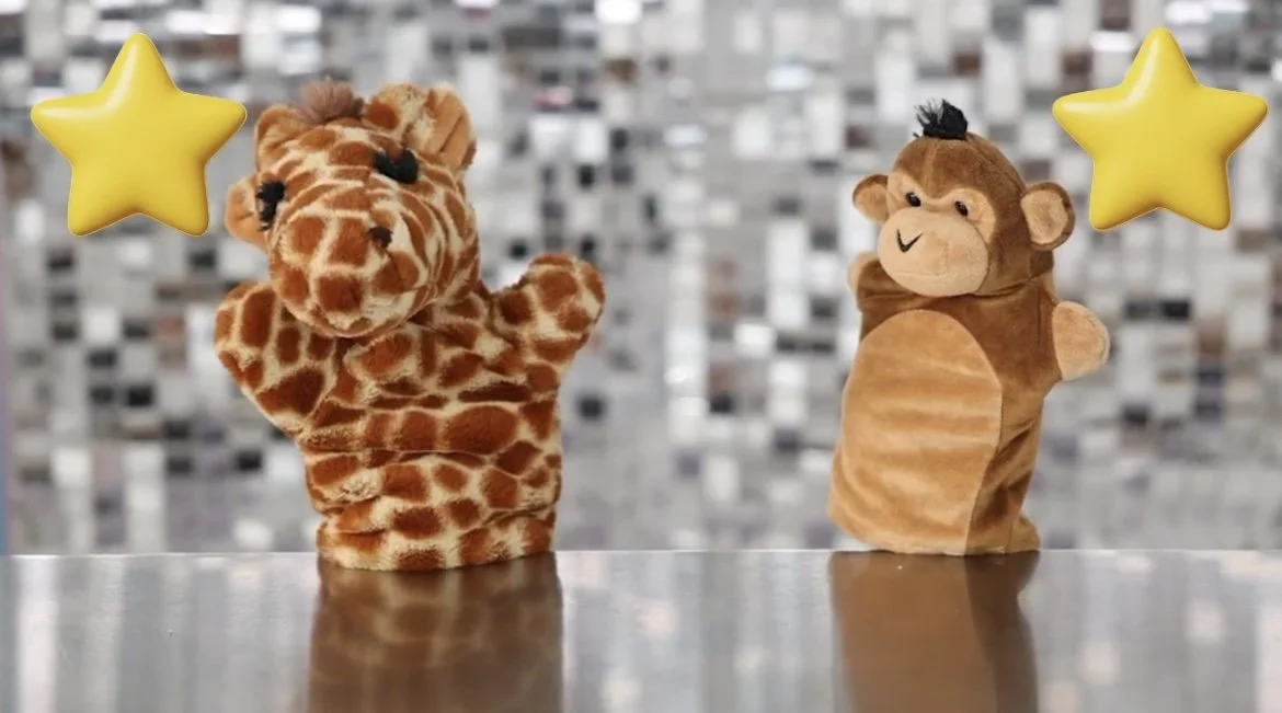 Two plush animal hand puppets, a giraffe on the left and a monkey on the right, with yellow star decorations above them, set against a metallic, reflective background.