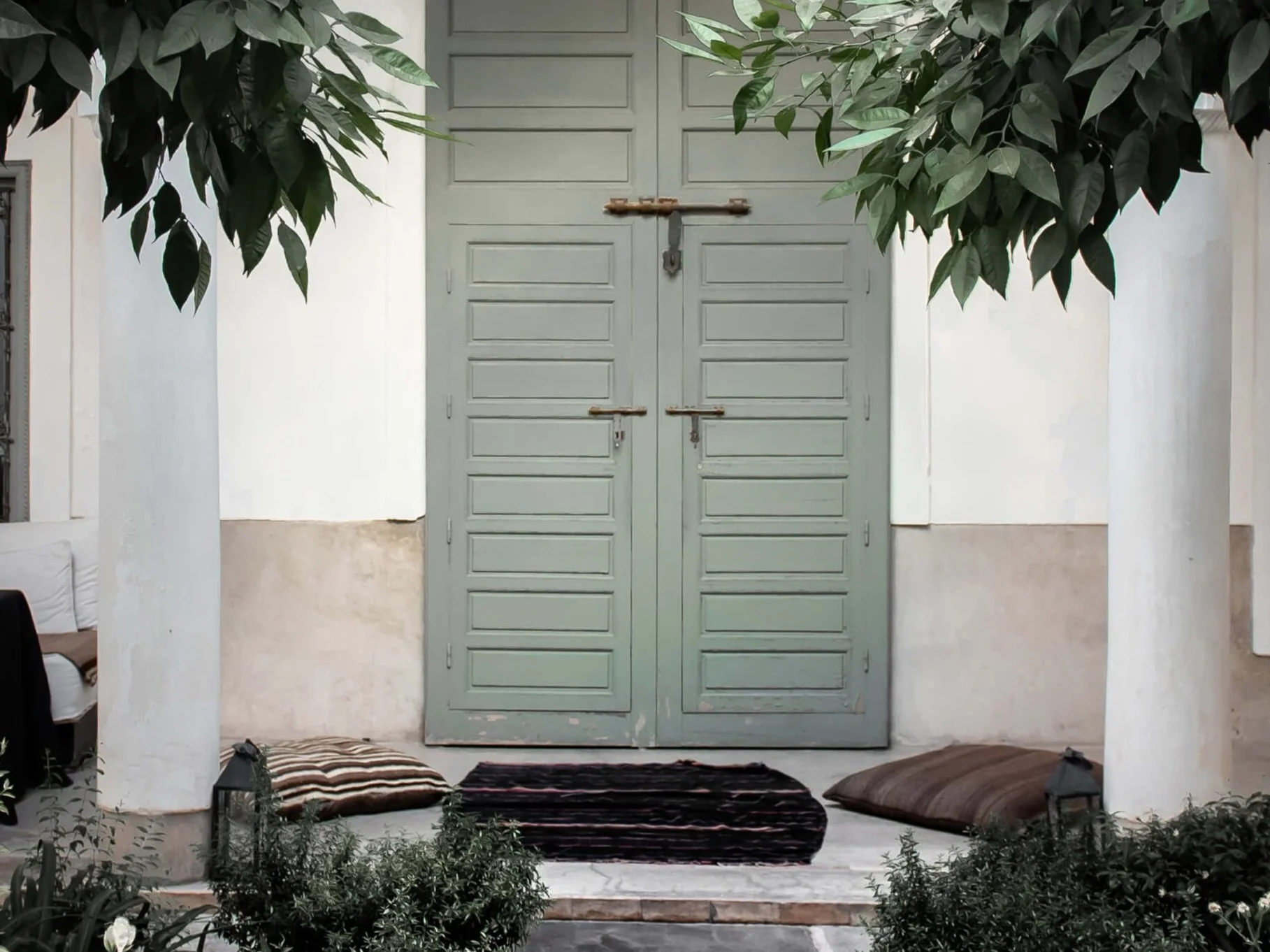 green double doors framed by white columns and green leaves