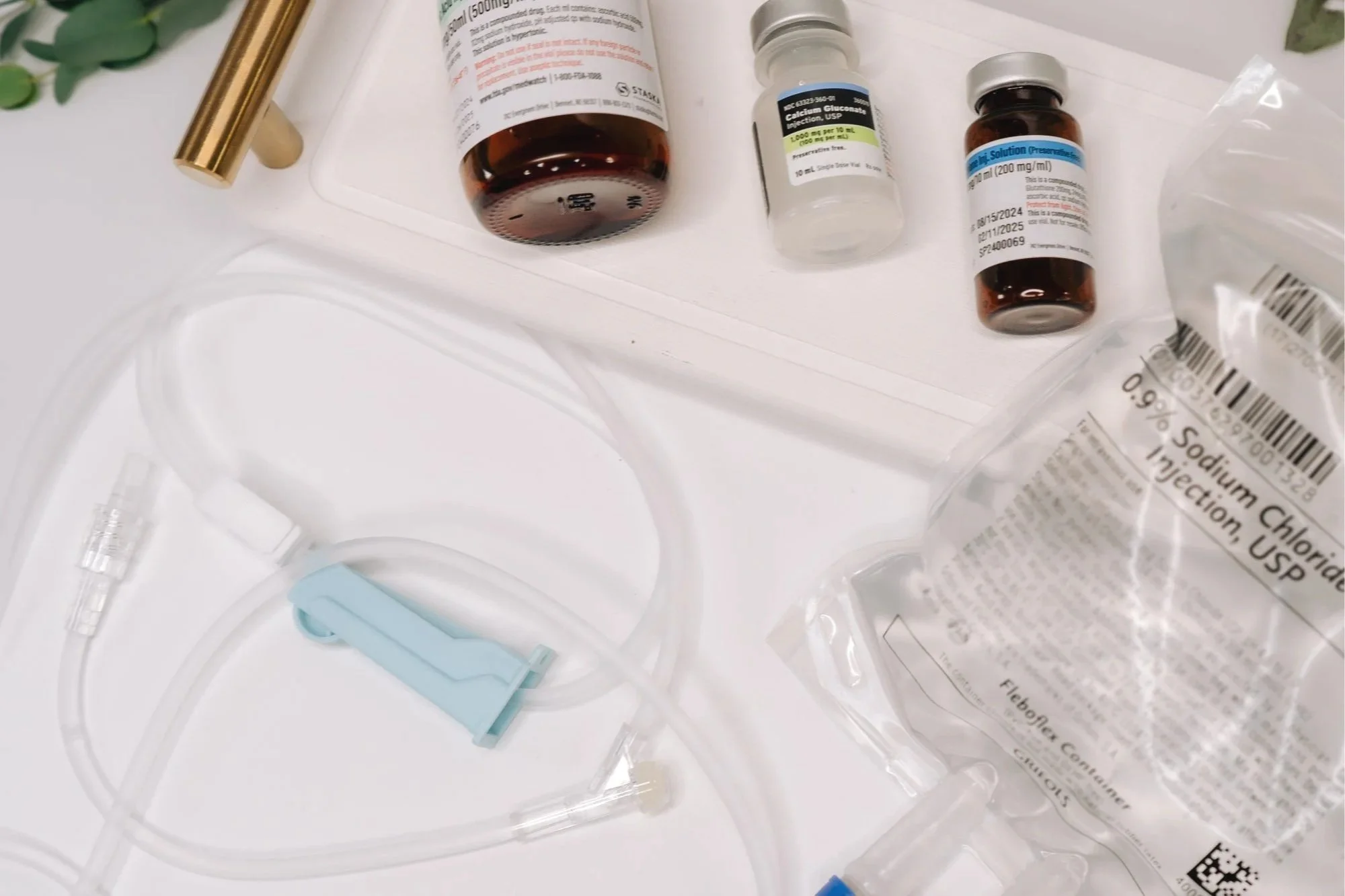 Medical supplies including vials of medication, a syringe, and a mask on a white surface.