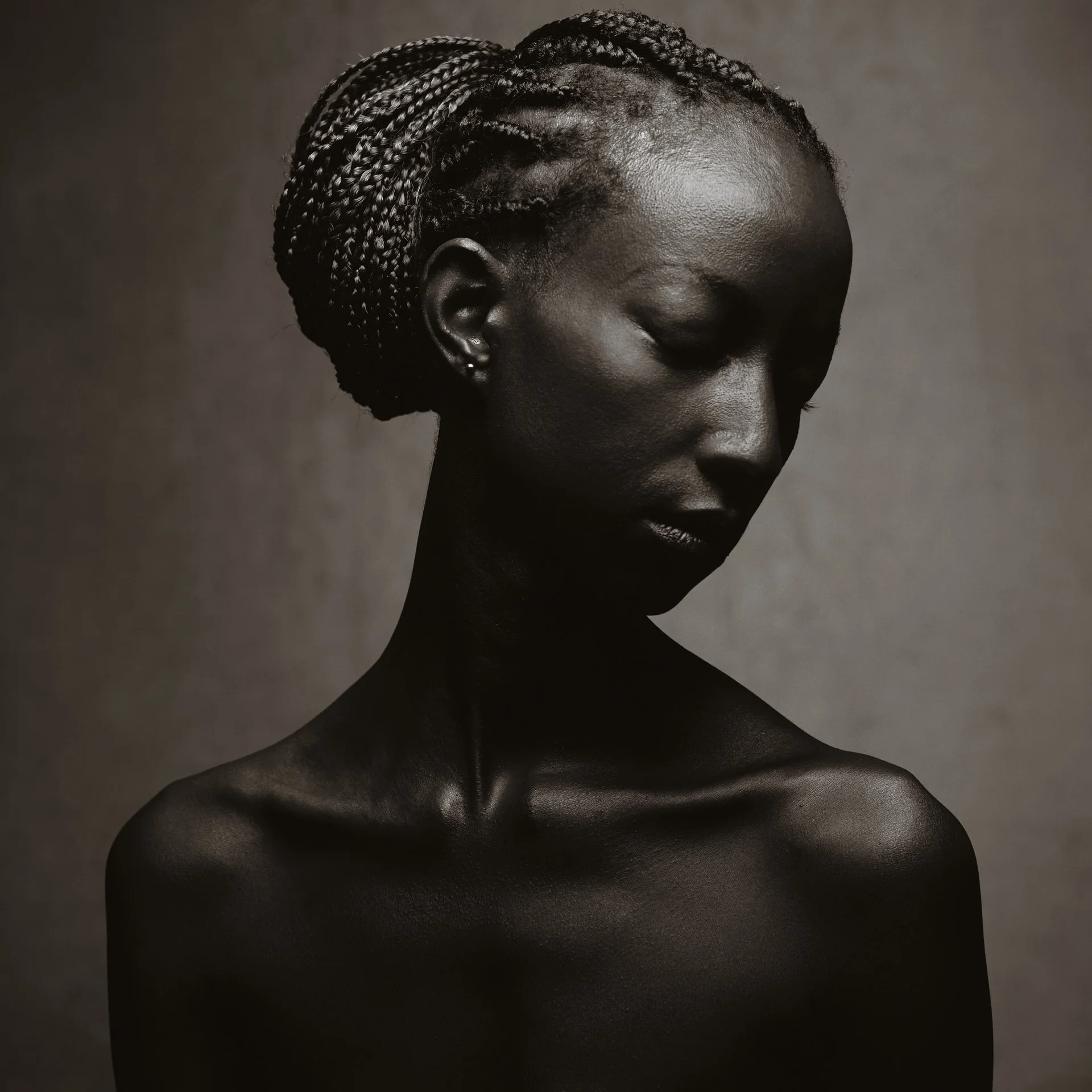 Portrait d'une femme noire aux cheveux tressés, vue de profil avec les yeux fermés.