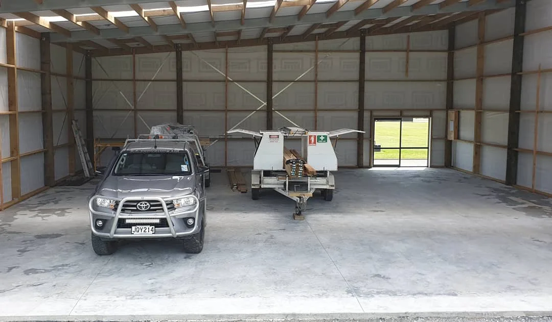 An unfinished warehouse with a silver Toyota truck and a drone delivery trailer inside.