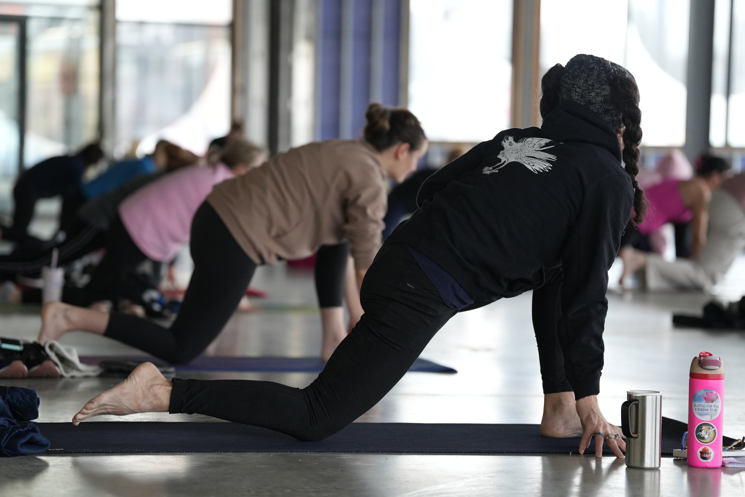 People participating in a yoga class in a studio, practicing a lunge pose on yoga mats.
