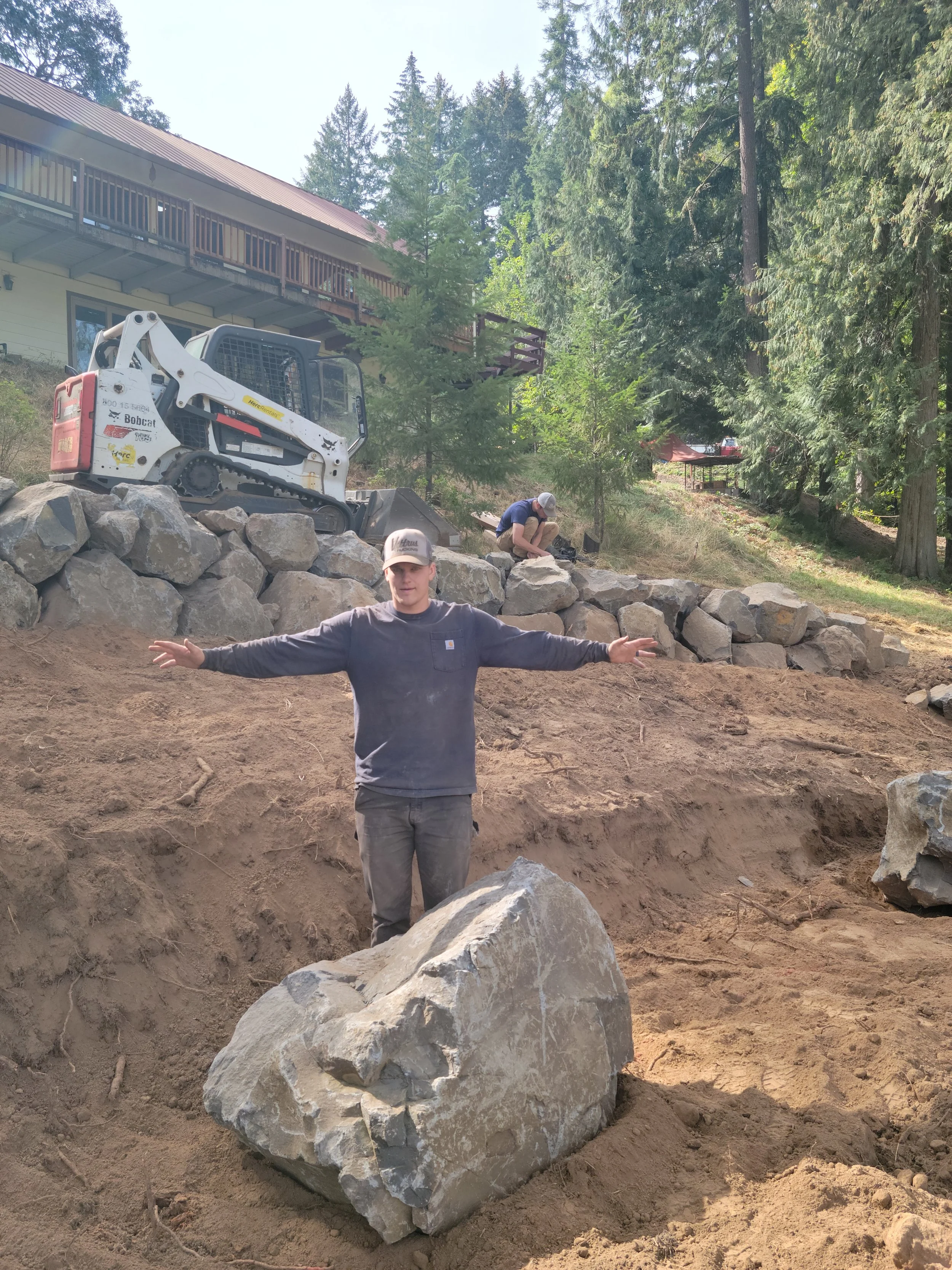 Jackson next to a bolder as he build a bolder wall for a client in Hillsboro Oregon.