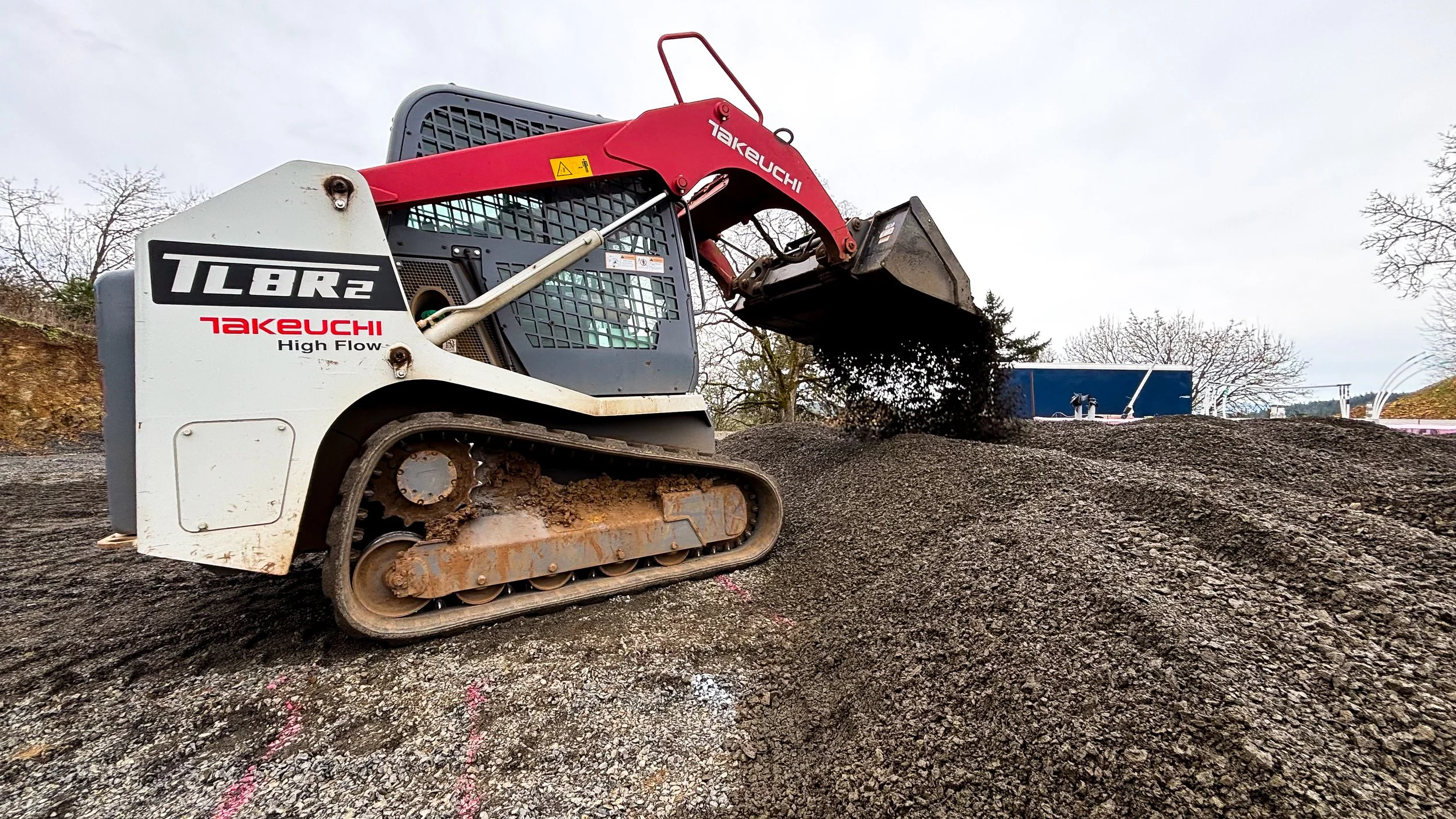 A small compact excavator moving dirt or gravel at a construction site.