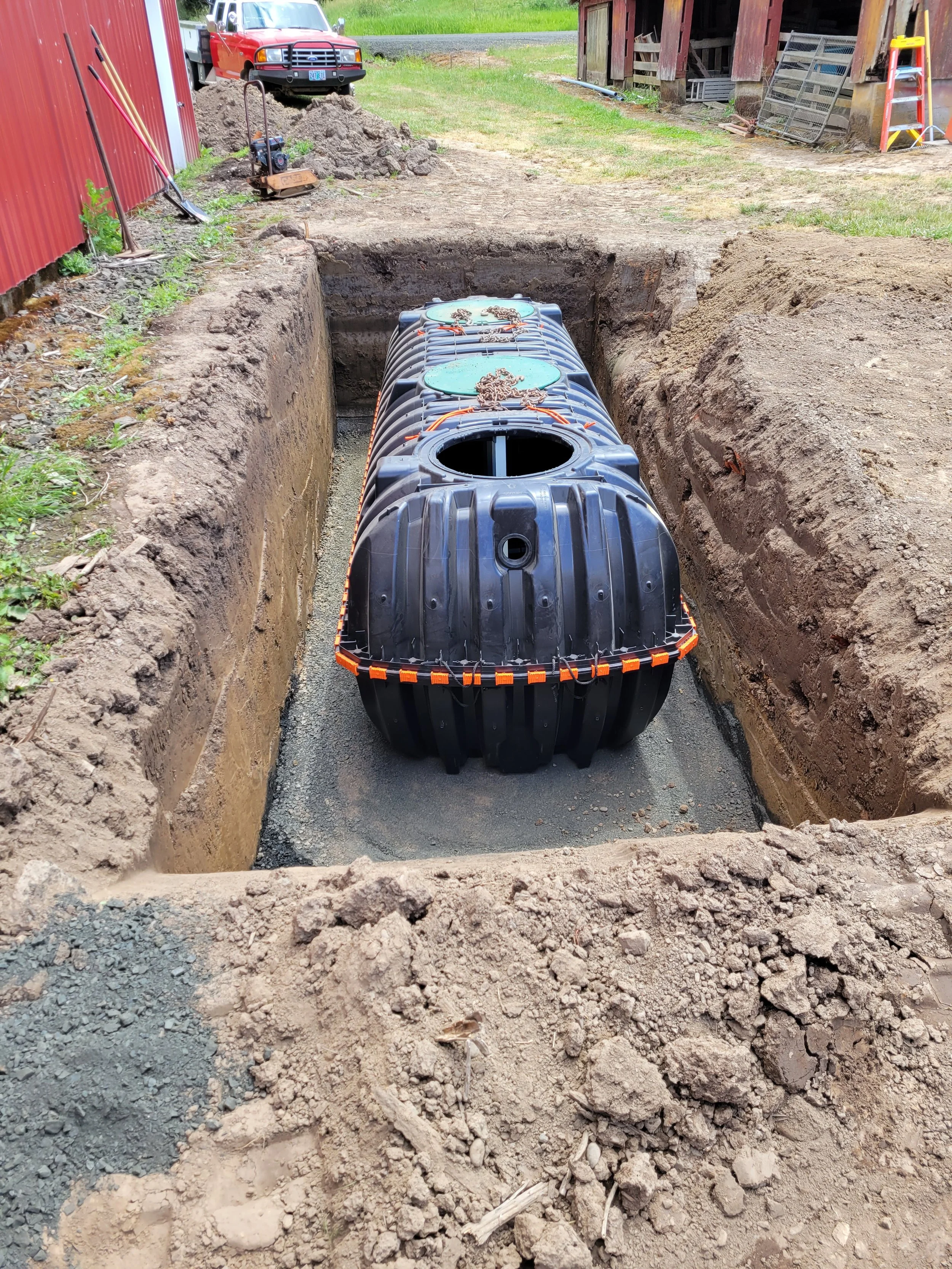 A large underground Septic Tank being installed in a trench with freshly excavated dirt on either side, set for construction or utility connection. Monmouth Oregon.