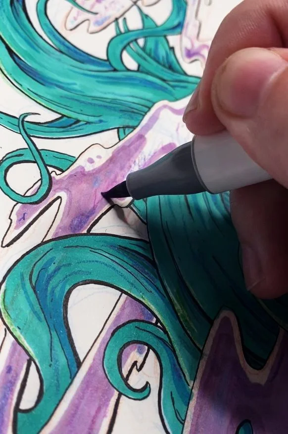 A close-up of a hand coloring a detailed illustration with a purple marker pen. The illustration features black ink with swirling teal and purple elements.