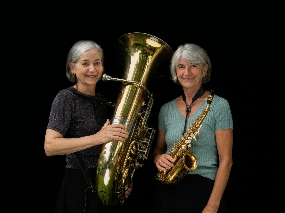 Two smiling women musicians holding a large brass tuba and a gold alto saxophone against a black background.