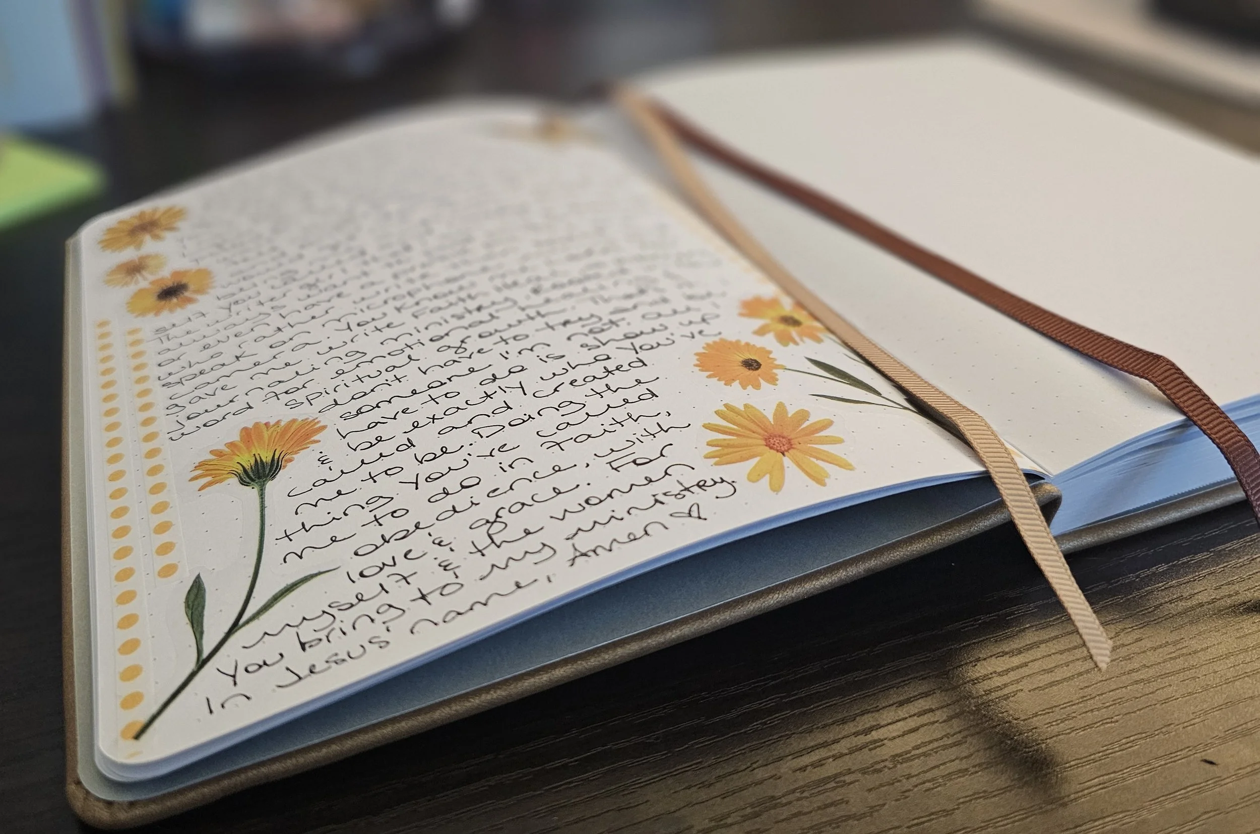 Open journal with handwritten text and yellow flowers illustrations, on a wooden surface.