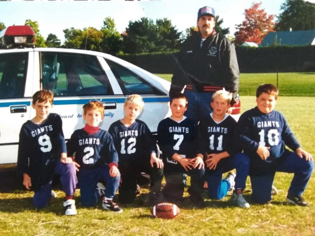 Sheriff Dave Favro co-founded the PAL Football program and stands with the team he coached