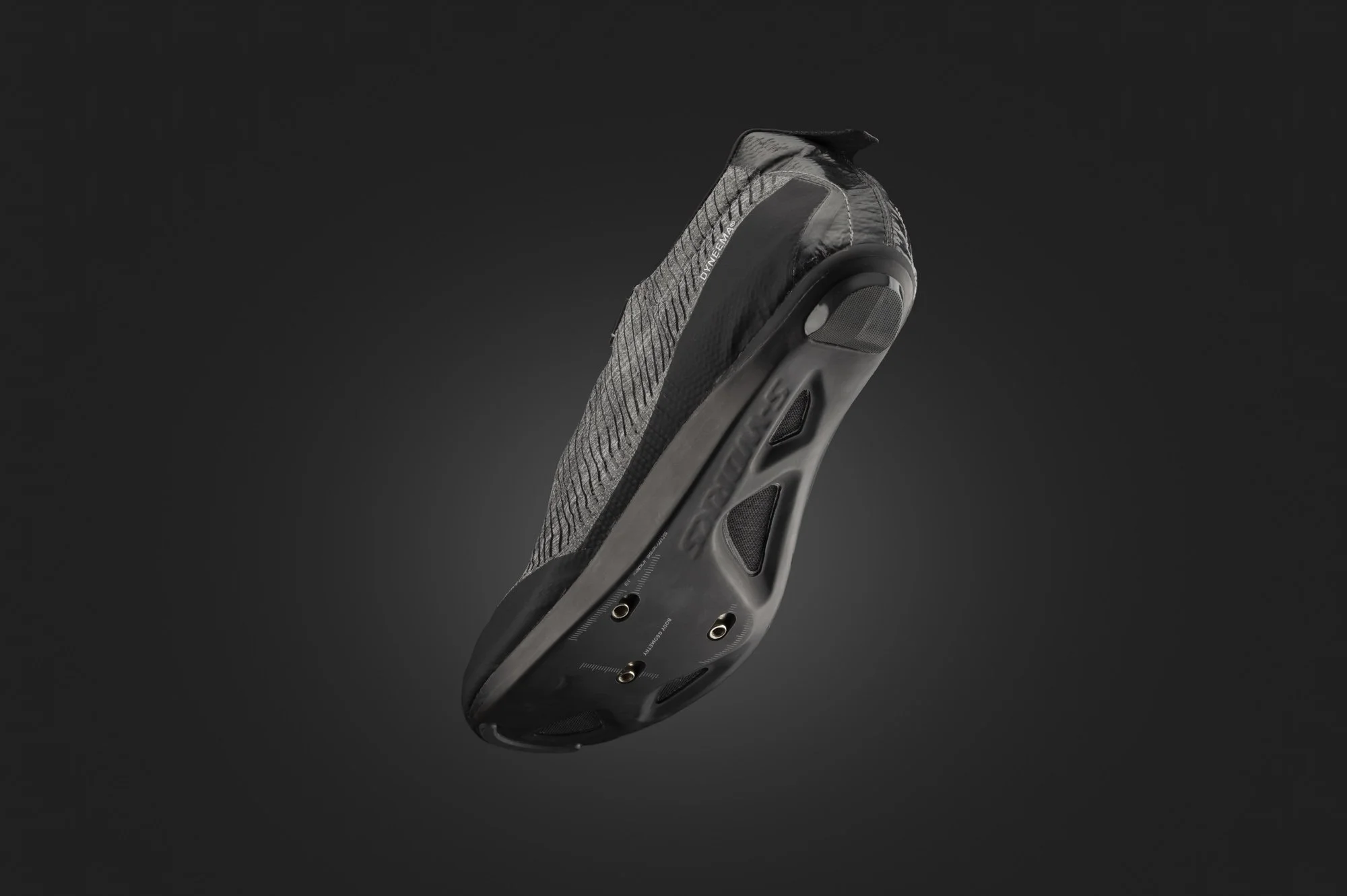 A black cycling shoe with carbon fiber sole and textured upper, isolated against a dark background.