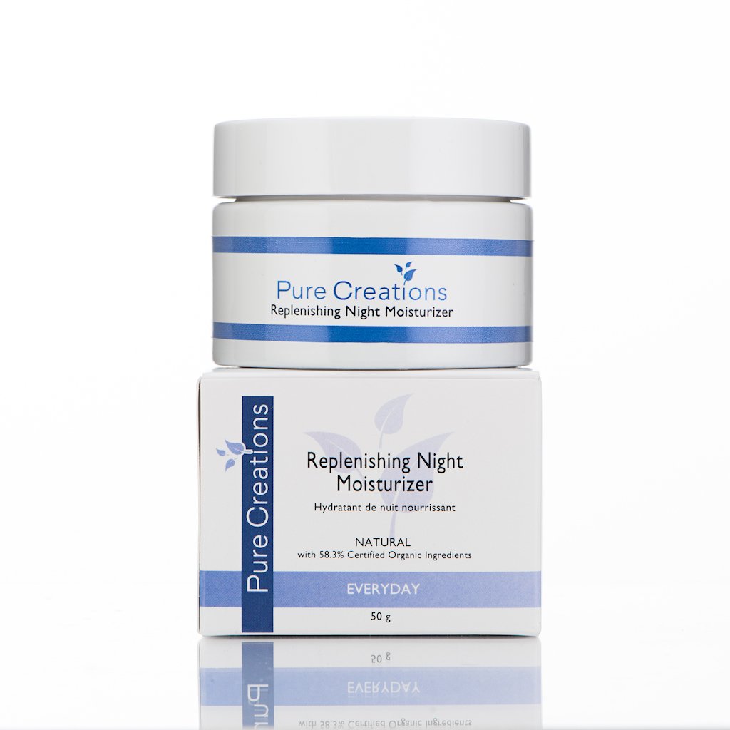 A white jar of Pure Creations Replenishing Night Moisturizer on top of a matching box, both with blue accents and text, set against a white background.