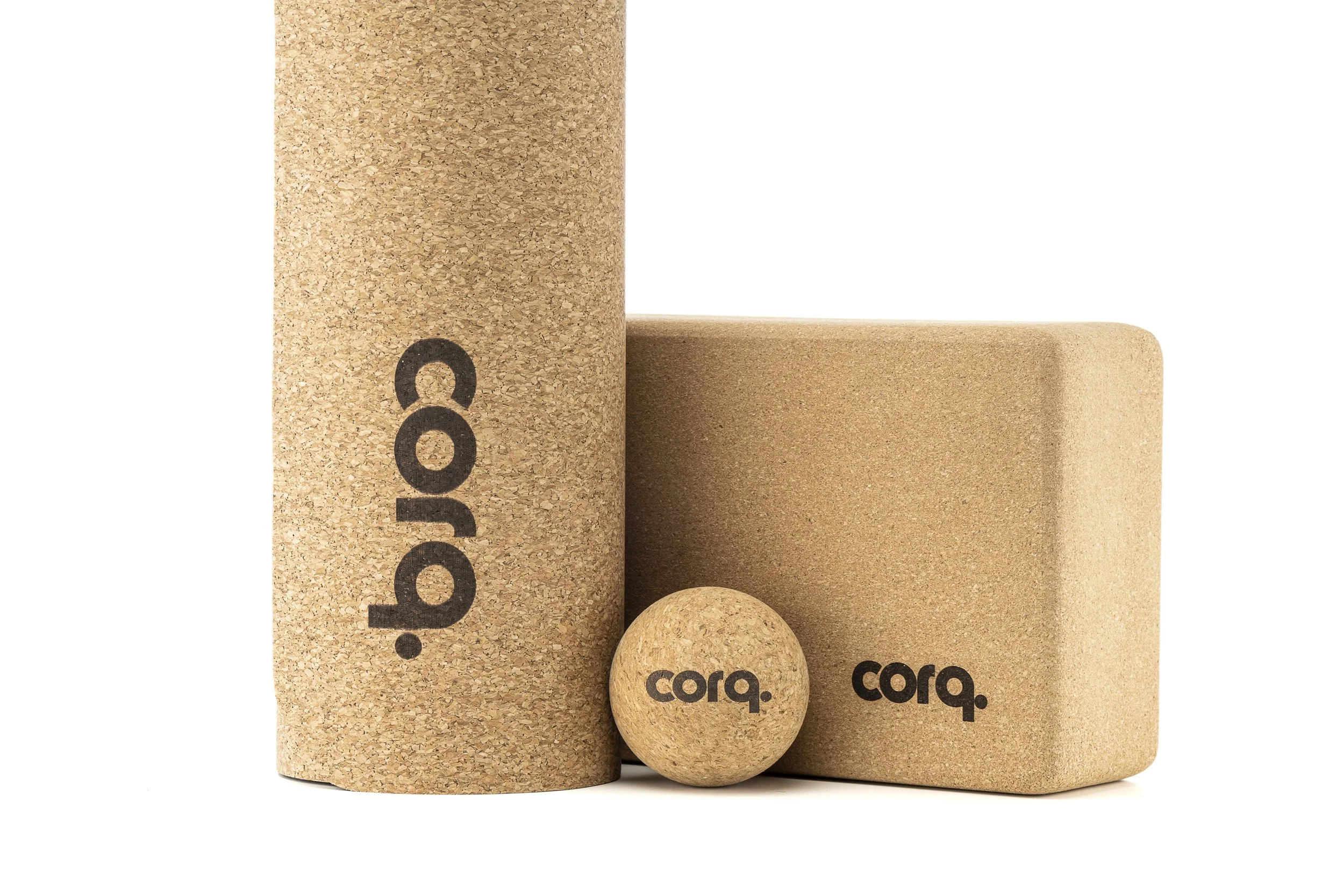 Cork yoga blocks and a cork massage ball with the brand name 'corq' printed on them, isolated on a white background.